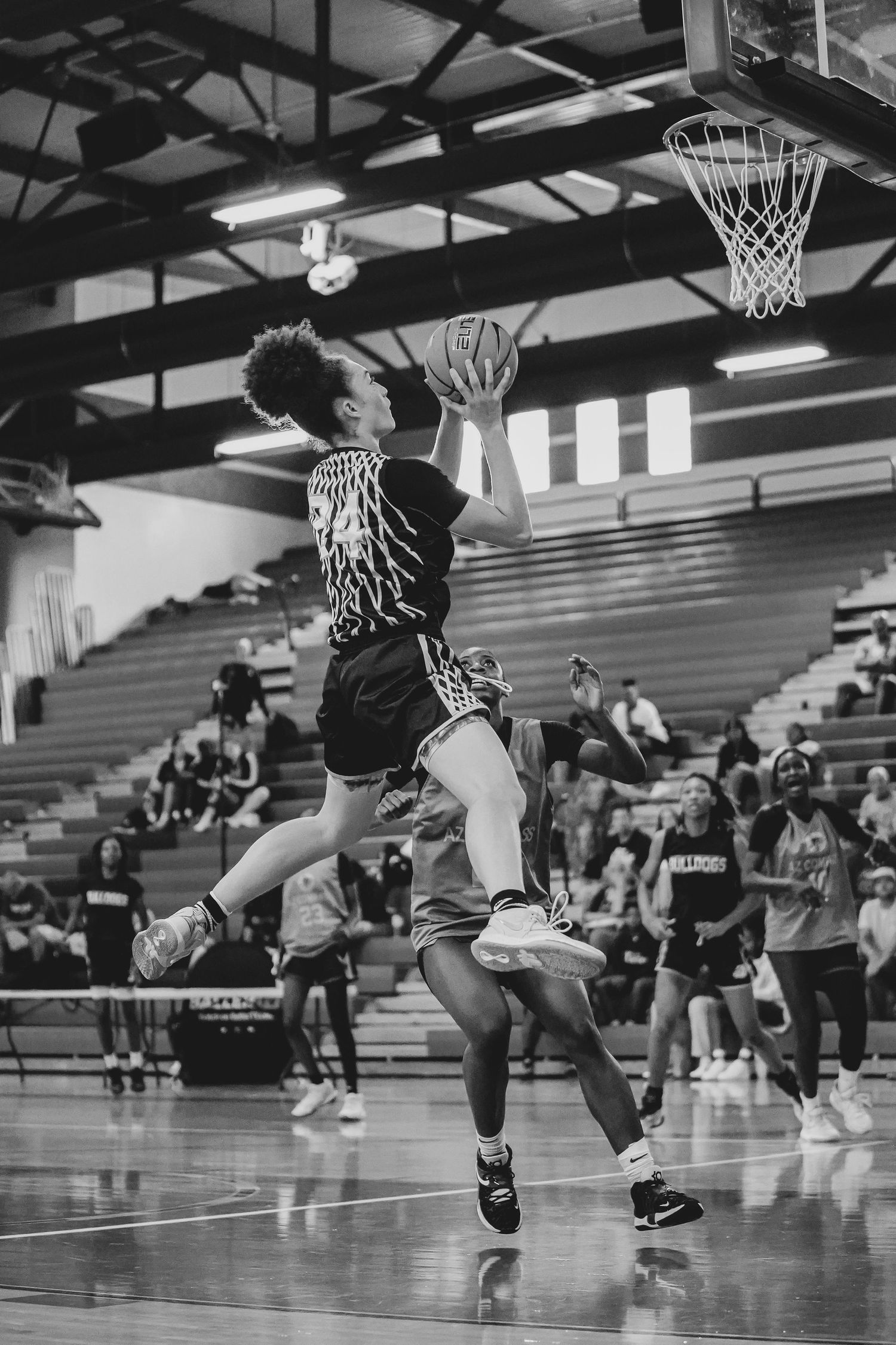 Basketball players practice jumping drills in gymnasium during team training session.