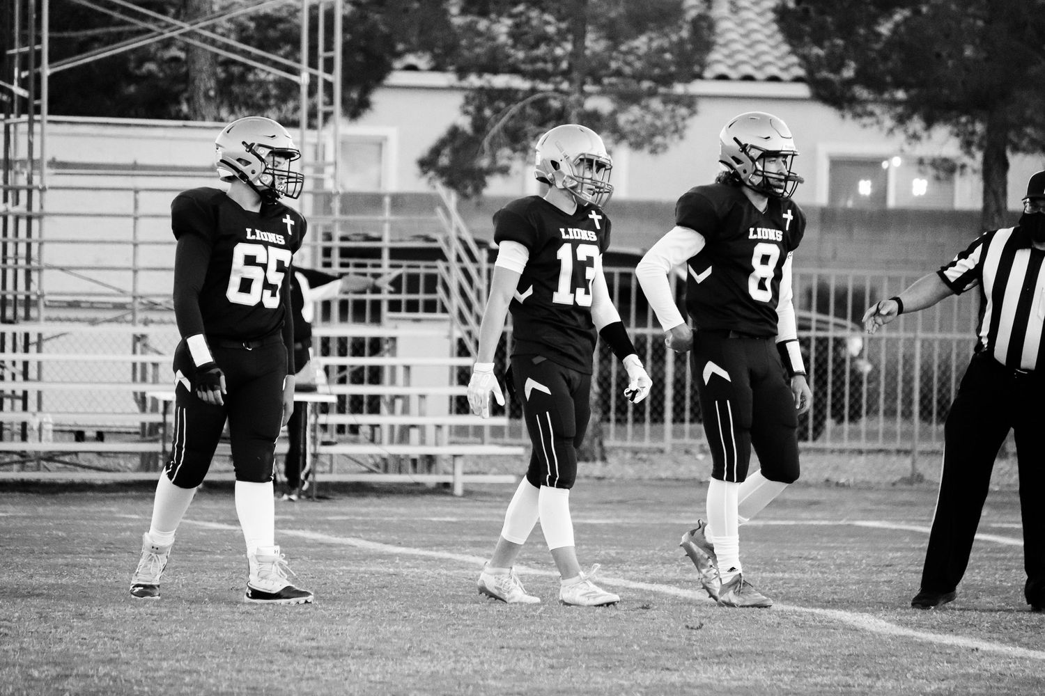 Black and white photo of football players and referee on field during game.