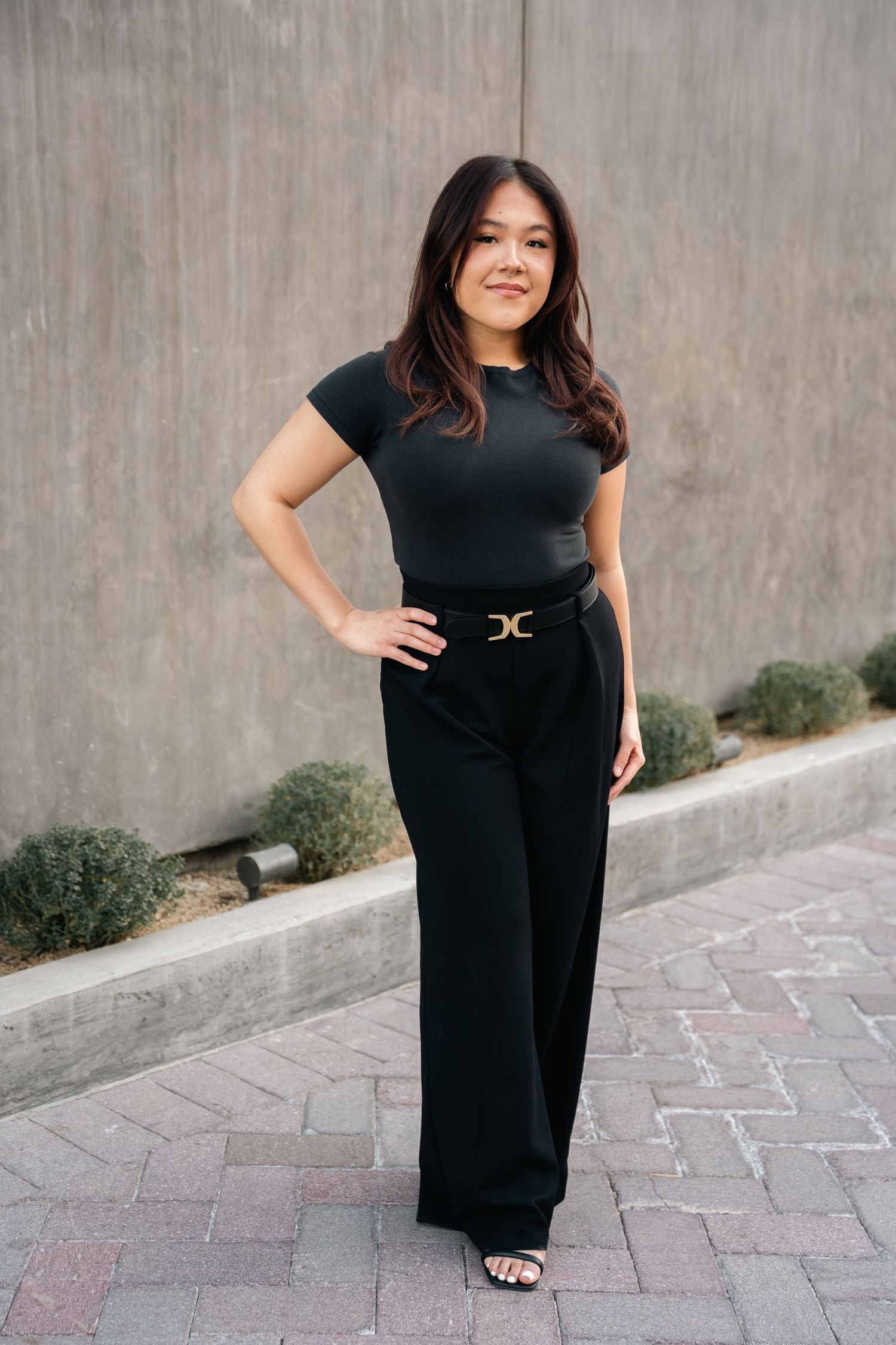 Elegant black jumpsuit styled with a statement belt and sandals.