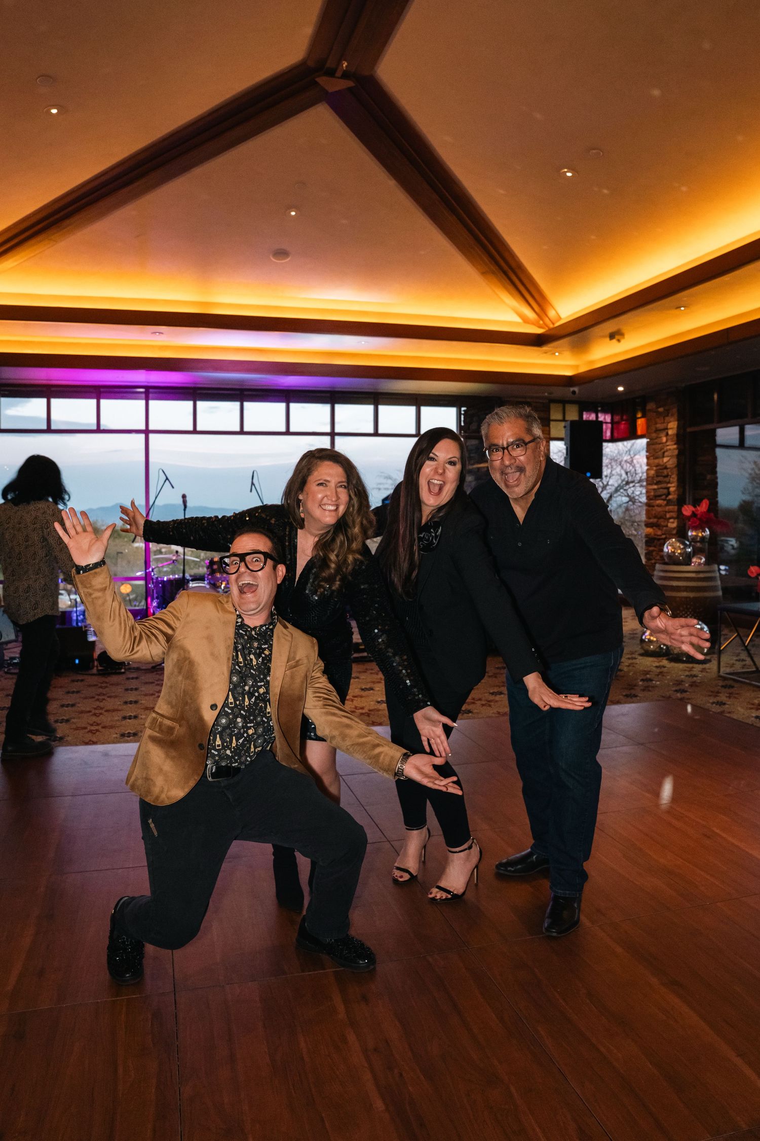 Group posing playfully at indoor event with mood lighting.