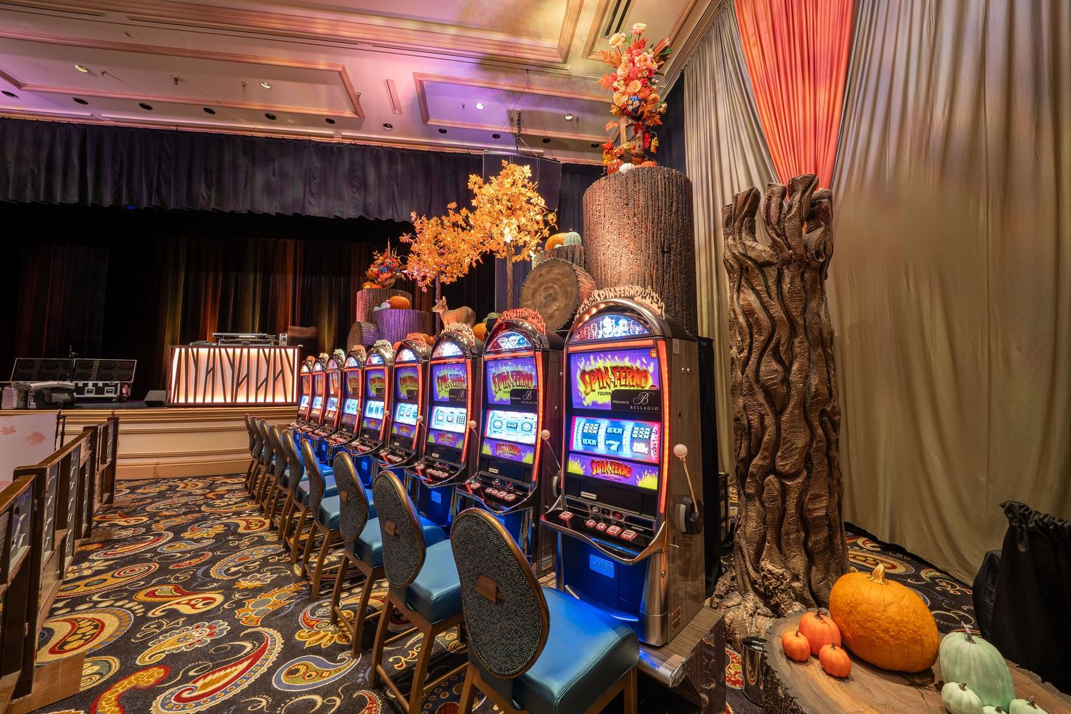Large casino gaming floor with slot machines and ornate decor illuminated by warm lighting.