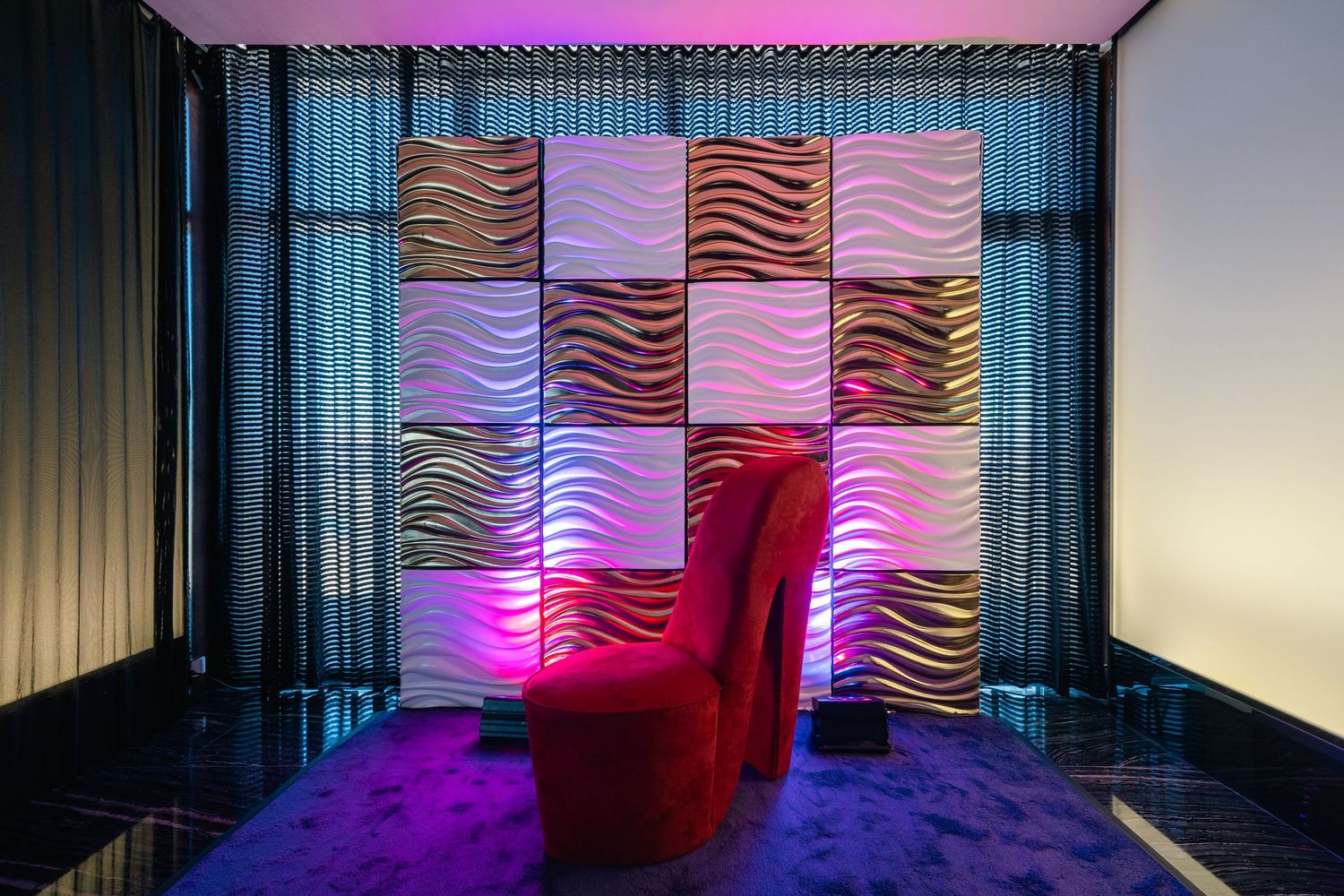 Event space with pink lighting and wavy wall panels creating an atmospheric ambiance.