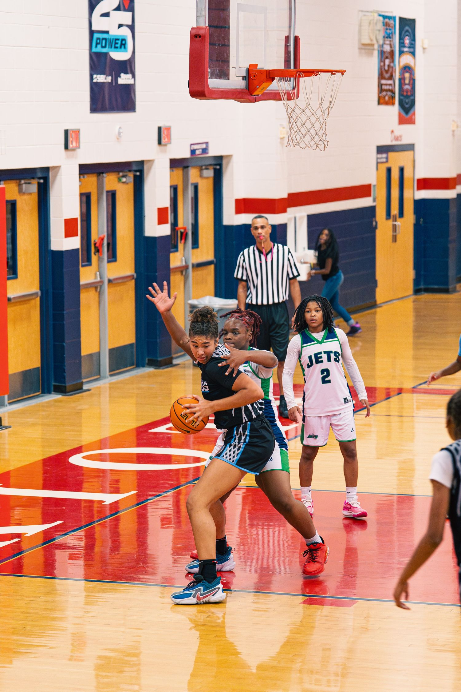 Basketball game action showing players in motion on red and yellow court.