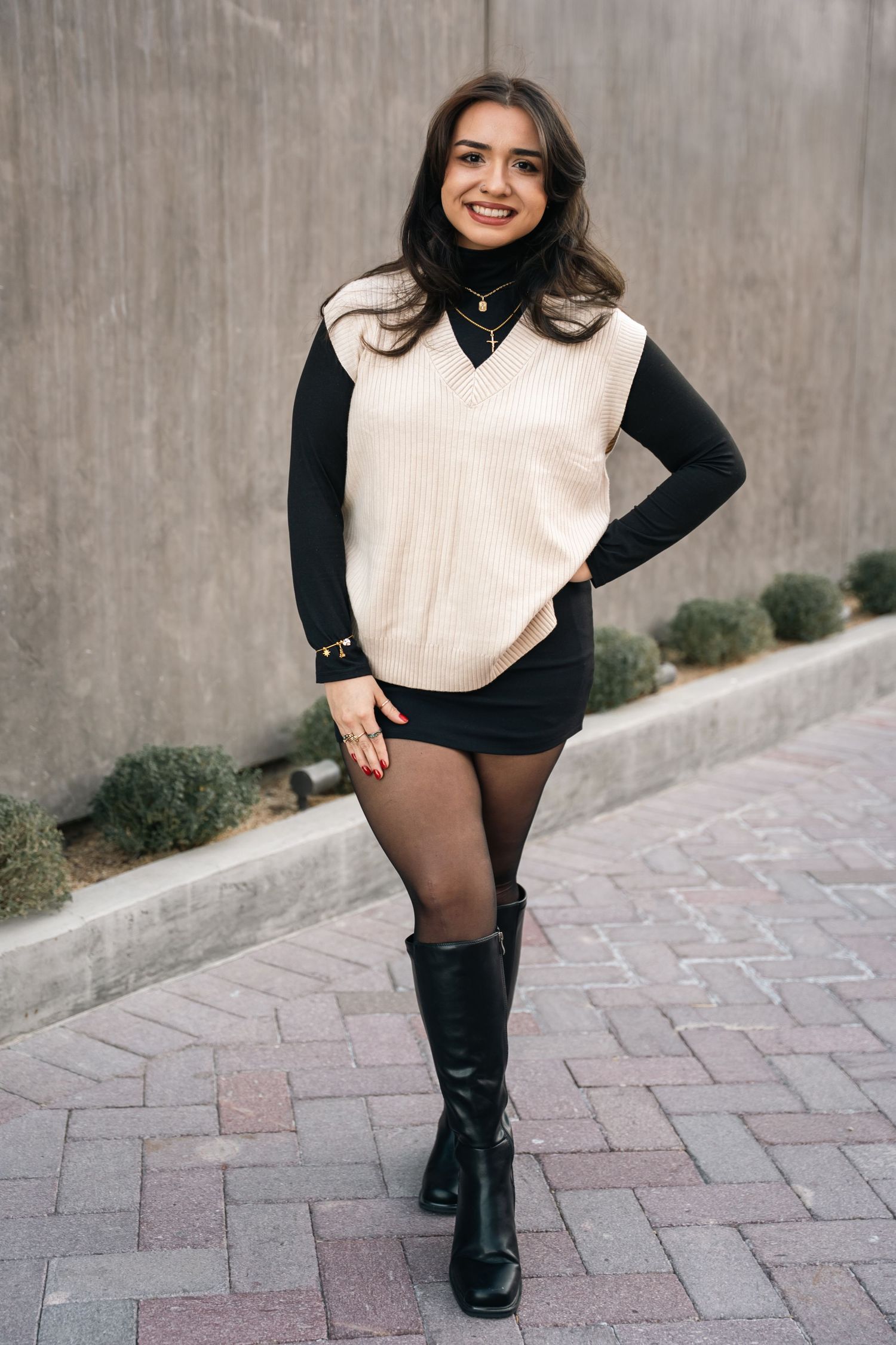 A stylish winter look with cream sweater vest, black turtleneck, shorts and knee-high boots.