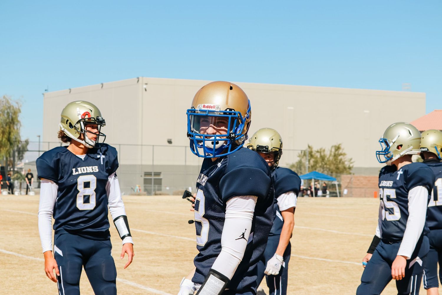 Football players in navy blue uniforms training on a sunny day.
