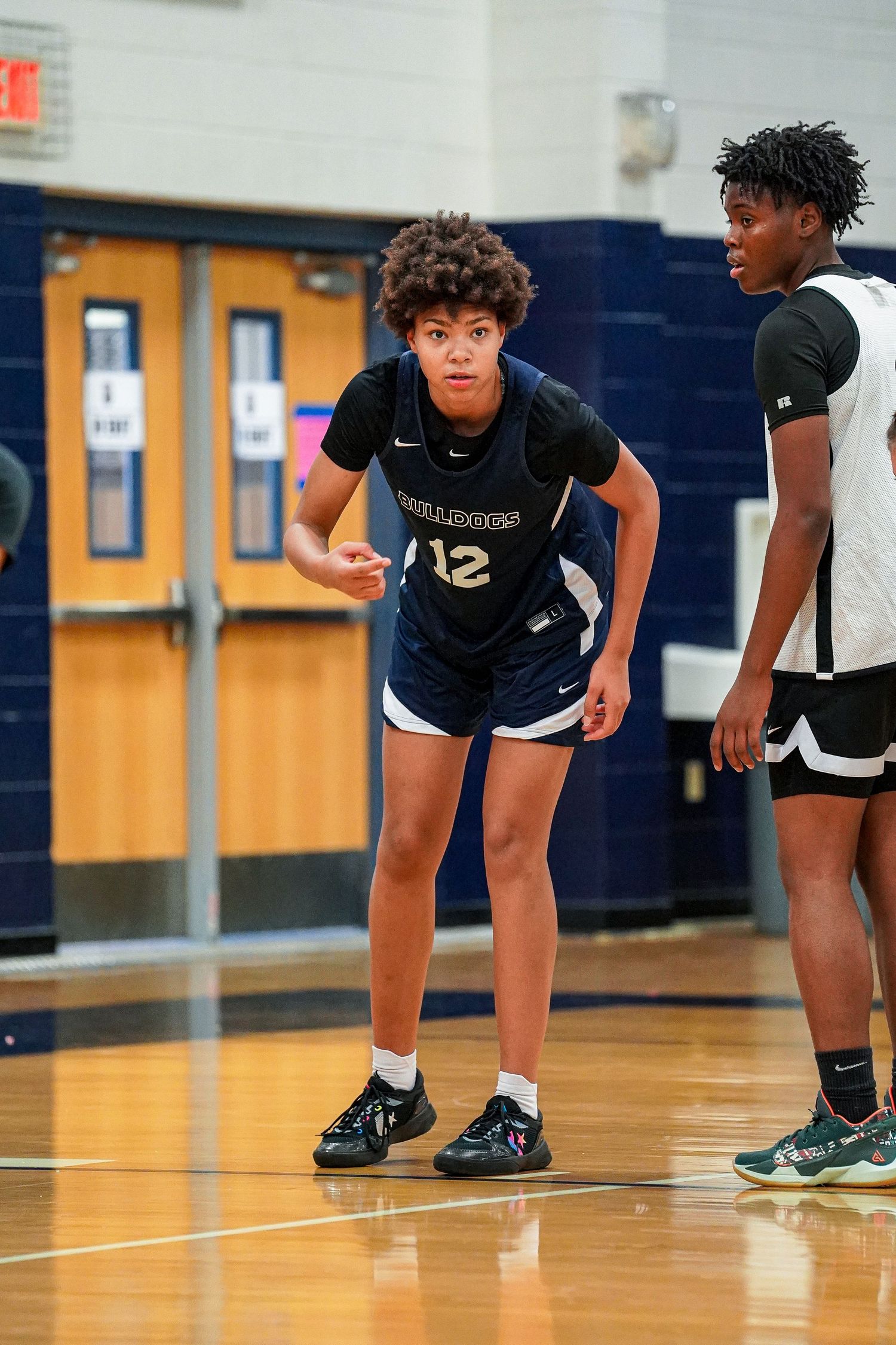 Basketball players in navy and white uniforms position themselves on the court during play.
