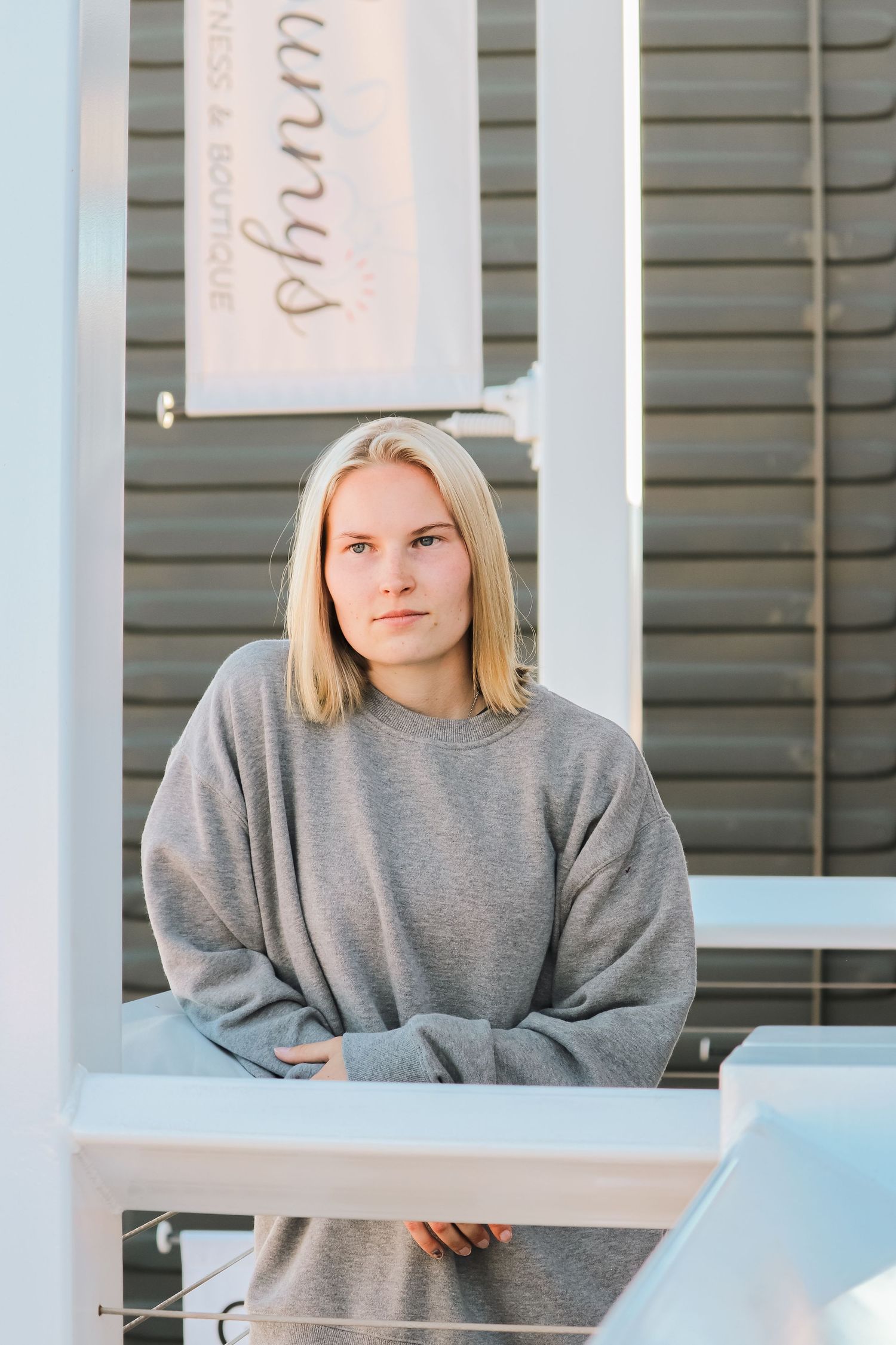 Portrait of a person in a gray sweatshirt standing near a structure with white pillars.