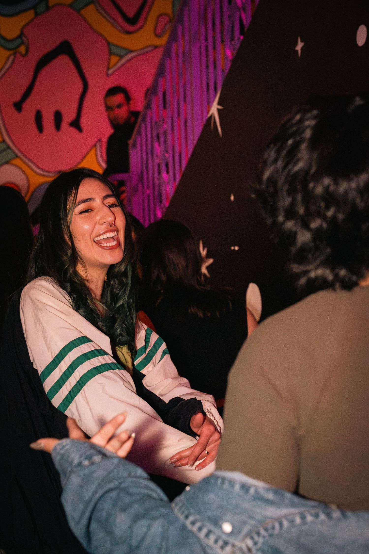 Candid moment of joyful interaction at nightclub with colorful graffiti wall.