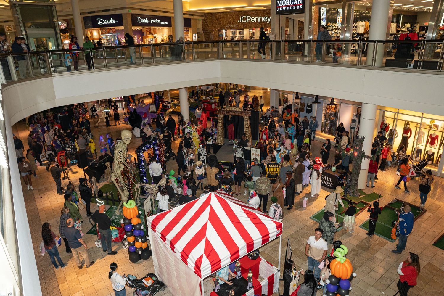 Aerial view of a crowded mall with red and white striped tent and Halloween decorations.