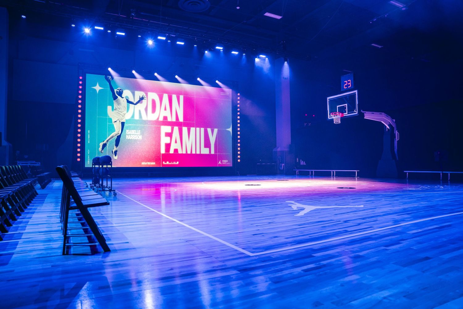 Basketball court illuminated with dramatic blue lighting and digital displays showing 'Family' text.