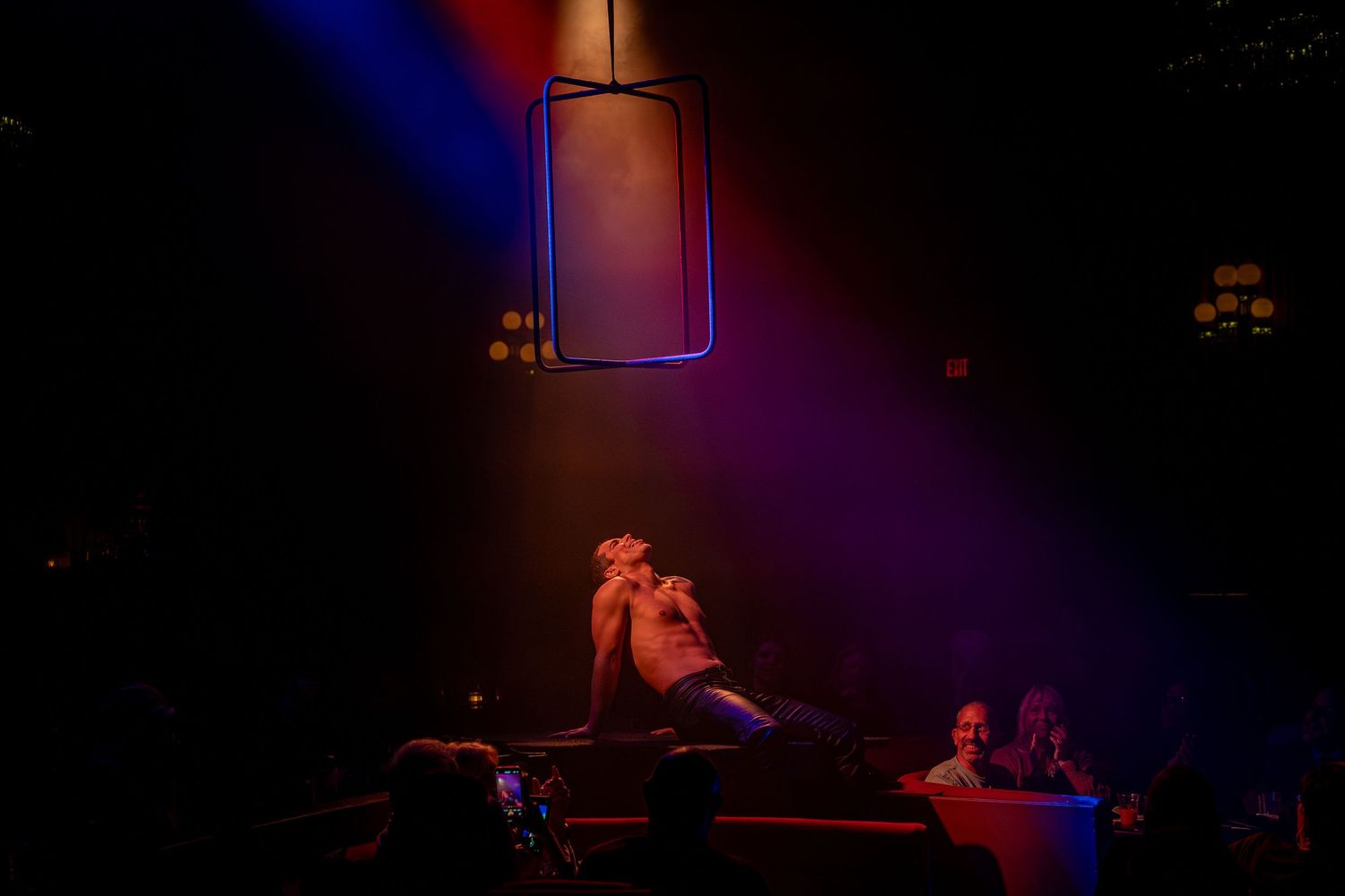 Dramatic silhouette of performers on stage with purple and blue spotlights.