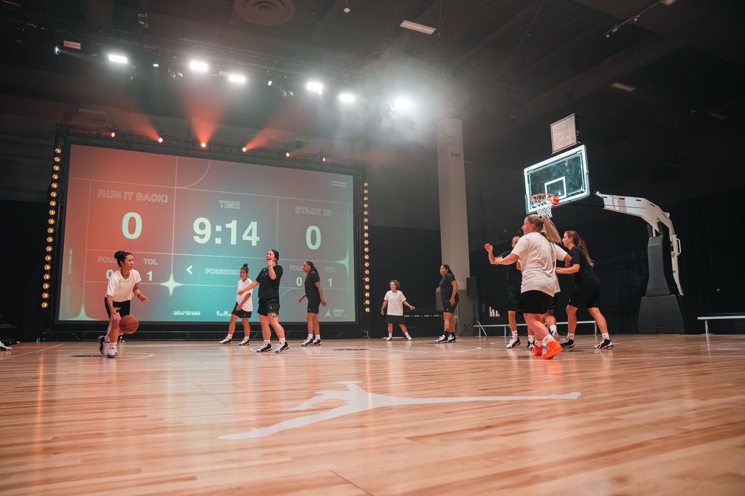 Basketball game in progress on indoor court with large digital scoreboard showing 9:14.