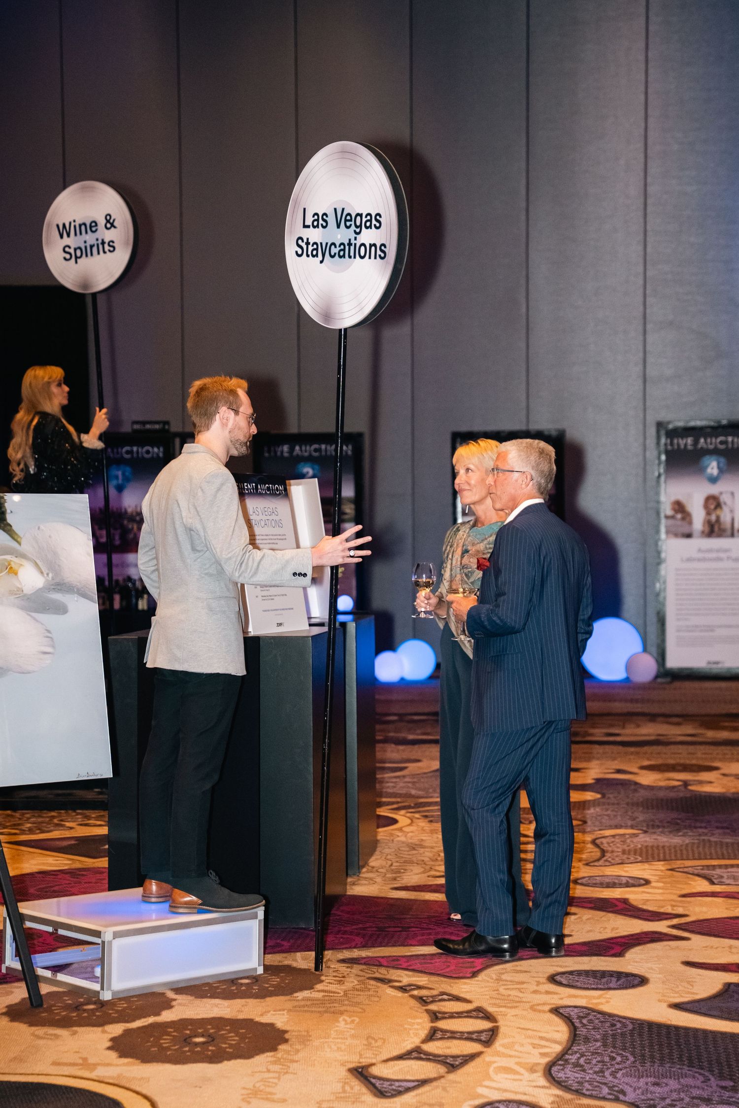 Exhibition space showing multiple display stands with attendees viewing presentations.