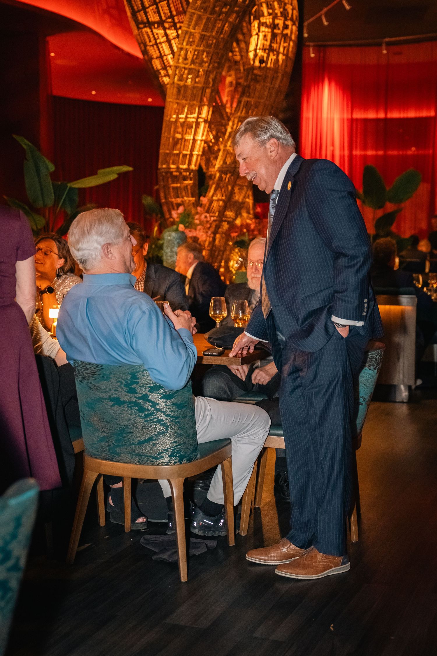 Guests socializing at dining tables in an upscale restaurant with distinctive architectural features.