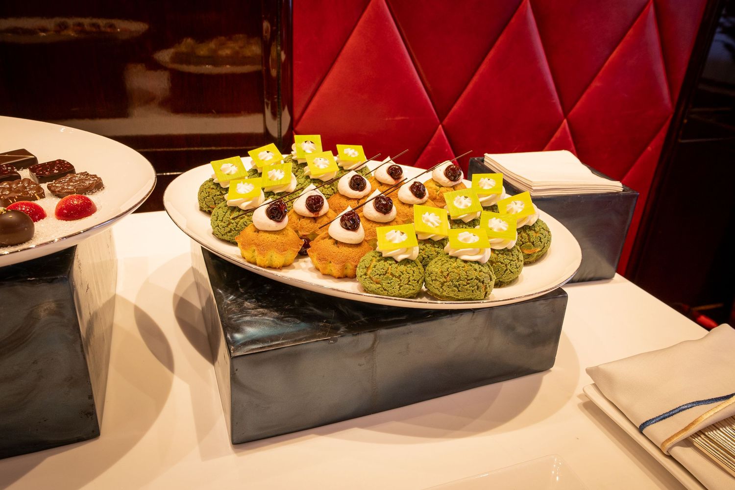 Colorful petit fours and mini desserts beautifully presented on a raised silver platform.