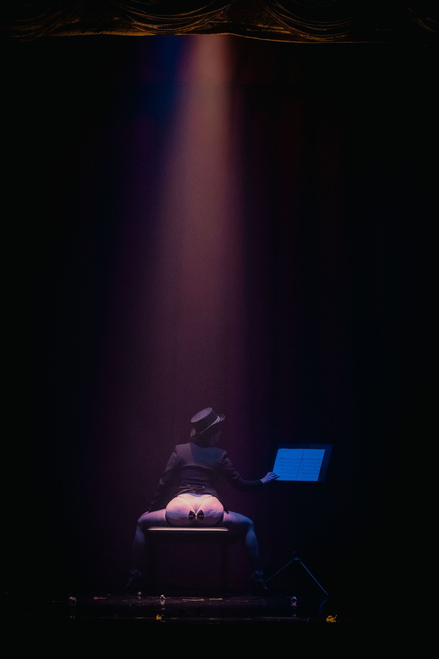 Silhouette of DJ performing under dramatic spotlight with laptop on stage.