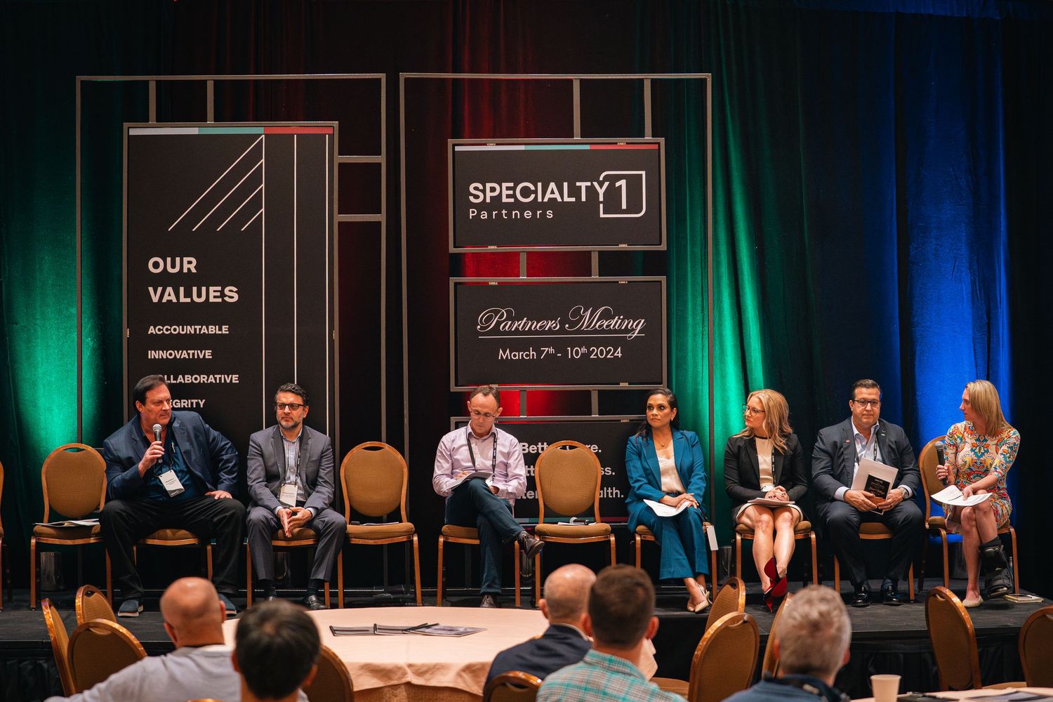 Panel discussion setup with multiple speakers seated on stage at professional conference.