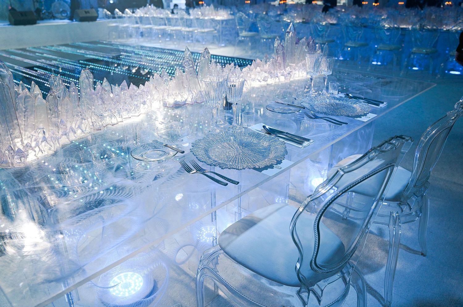 Crystal clear table settings with ice-inspired decor and blue ambient lighting.
