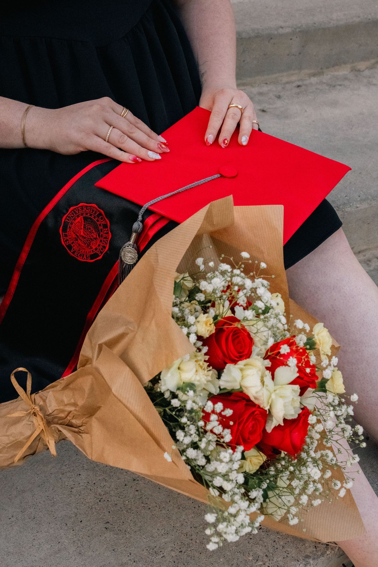 Graduation bouquet with red roses and white baby's breath wrapped in brown paper.