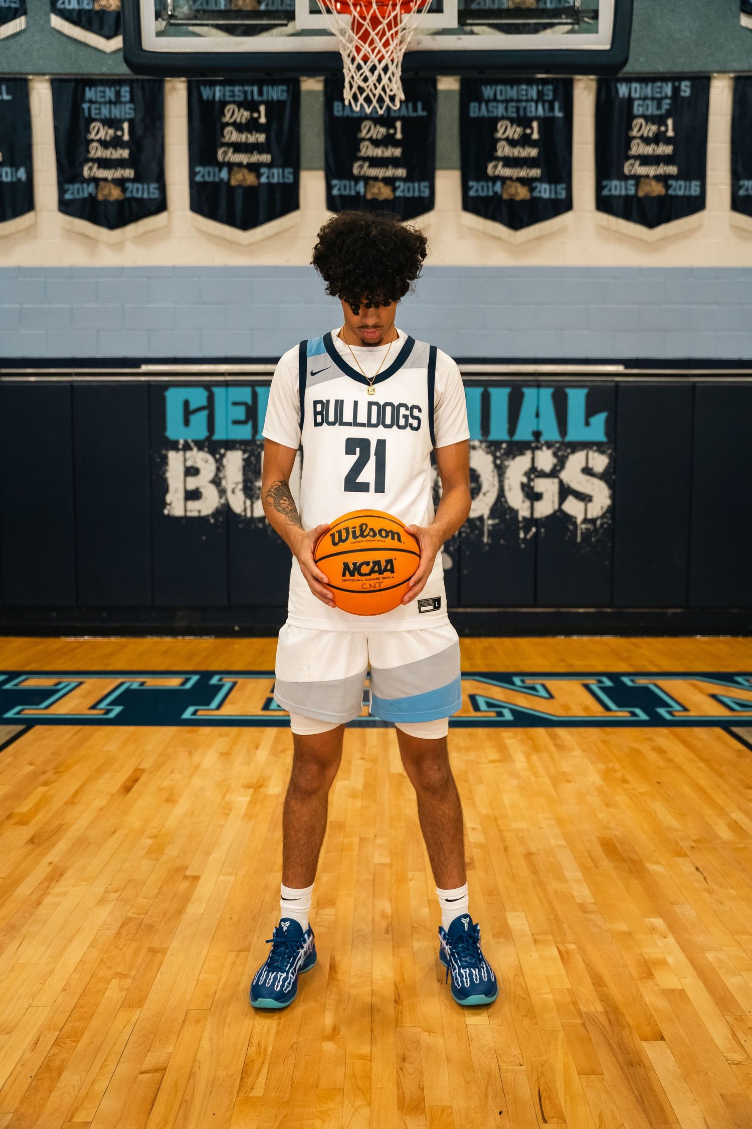 Basketball player holding Wilson NCAA ball in white Bulldogs jersey number 21.