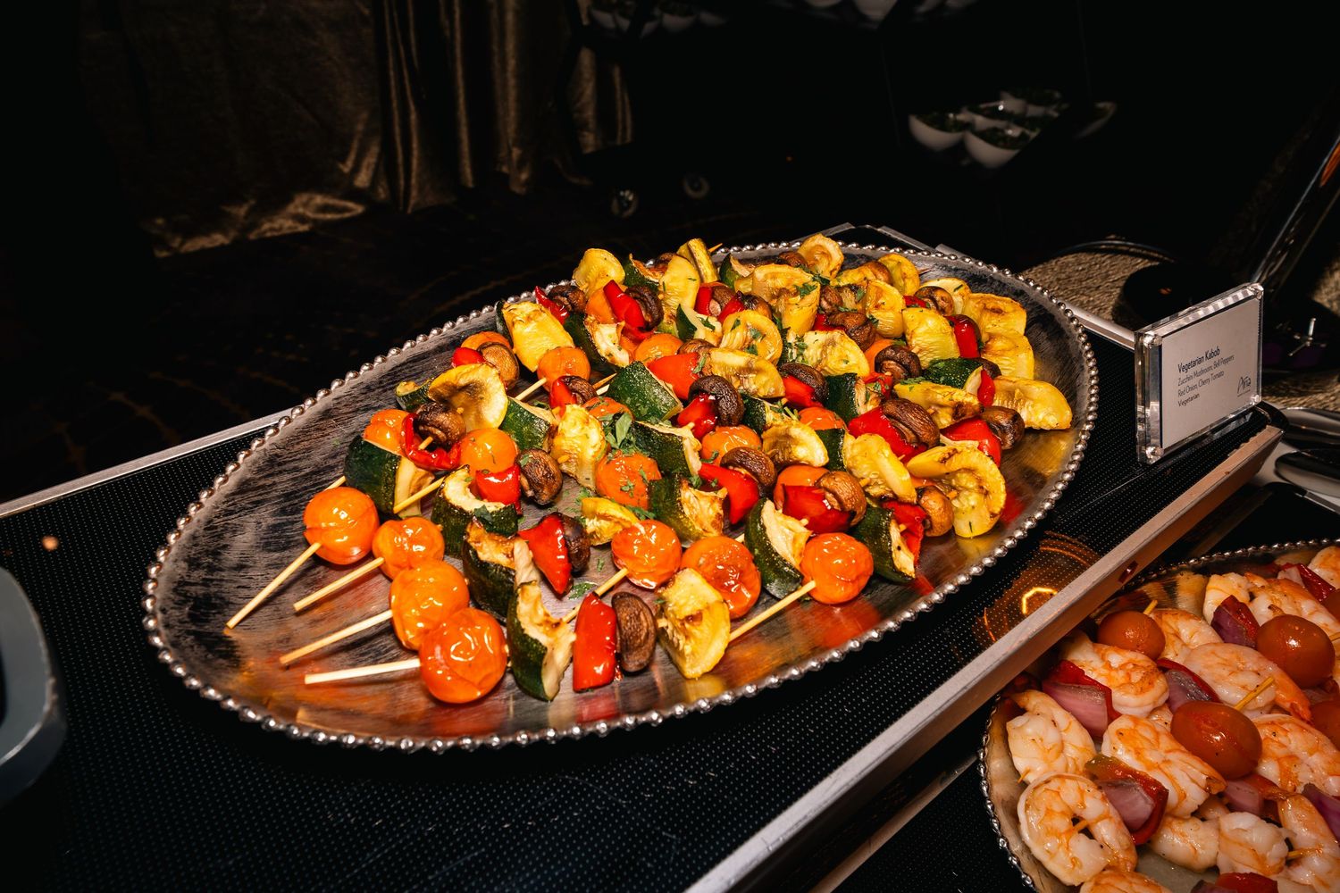 Colorful grilled vegetable and meat skewers arranged on silver serving platter.