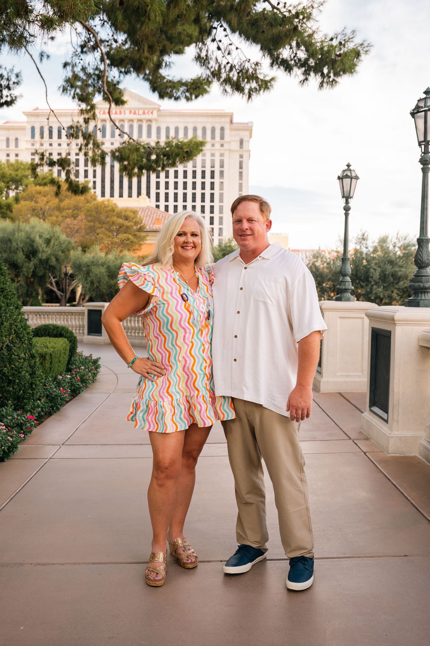 Casual outdoor photoshoot on concrete walkway with classic architecture and buildings in background.