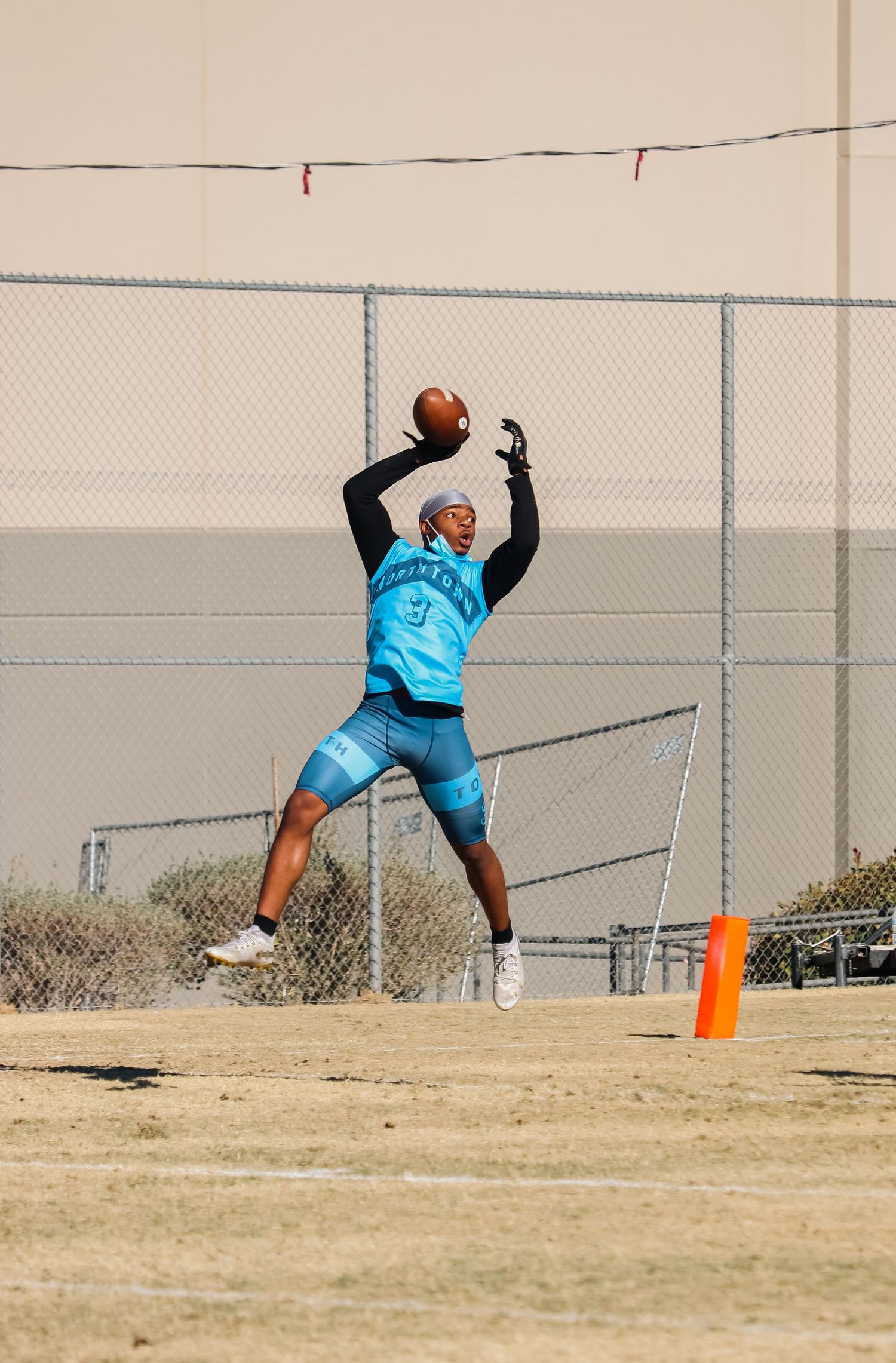 Athletic training sequence showing dynamic jumping and catching movements on outdoor field.