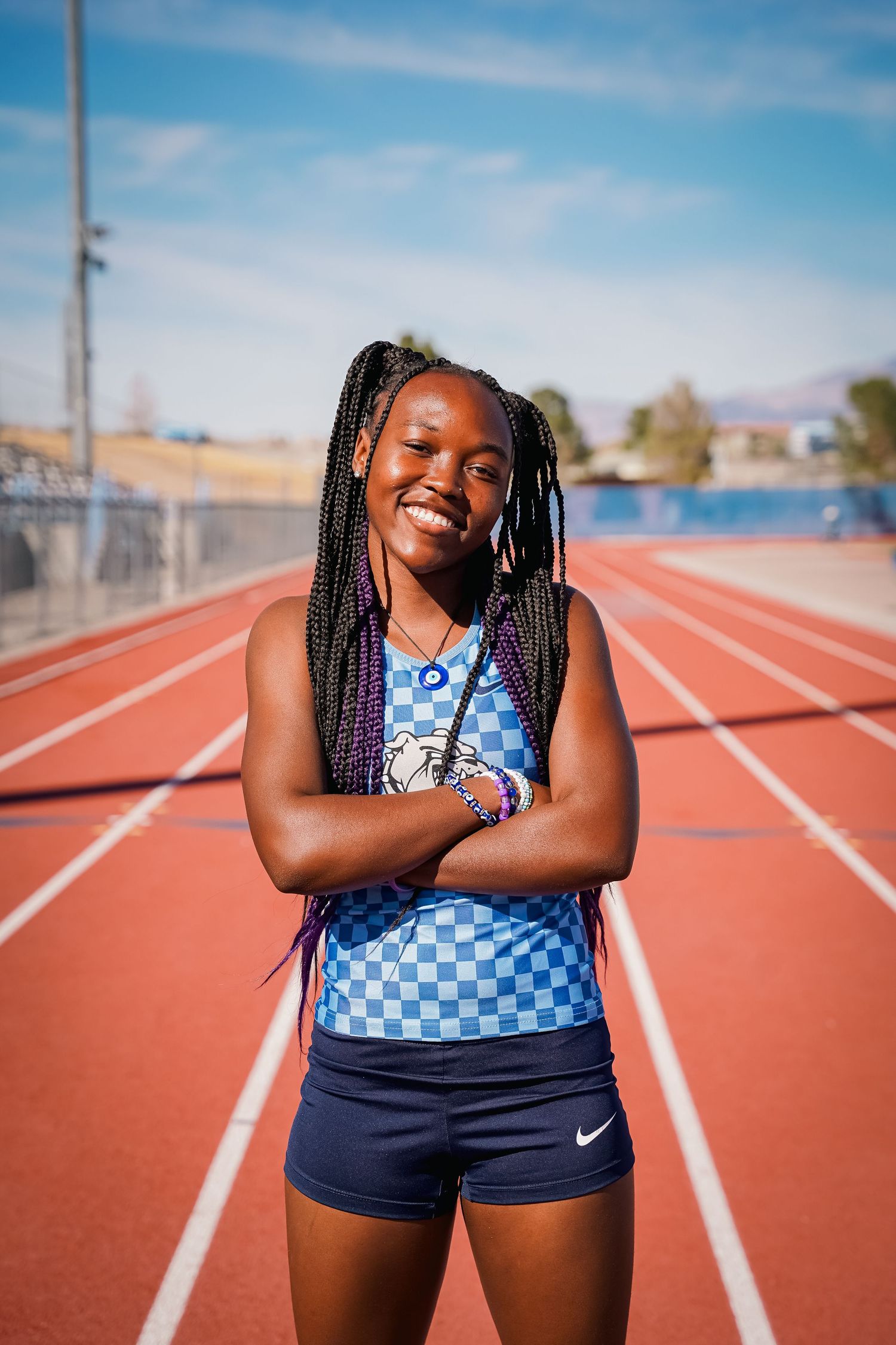 Athlete in checkered blue uniform poses confidently on running track.