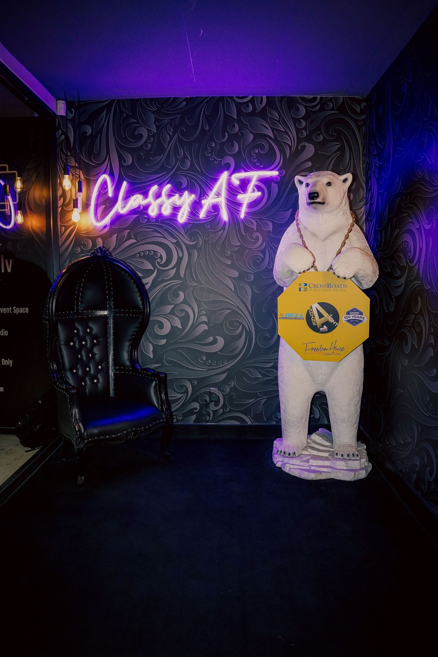 Neon 'Classy AF' sign illuminates dark room with white polar bear statue display.