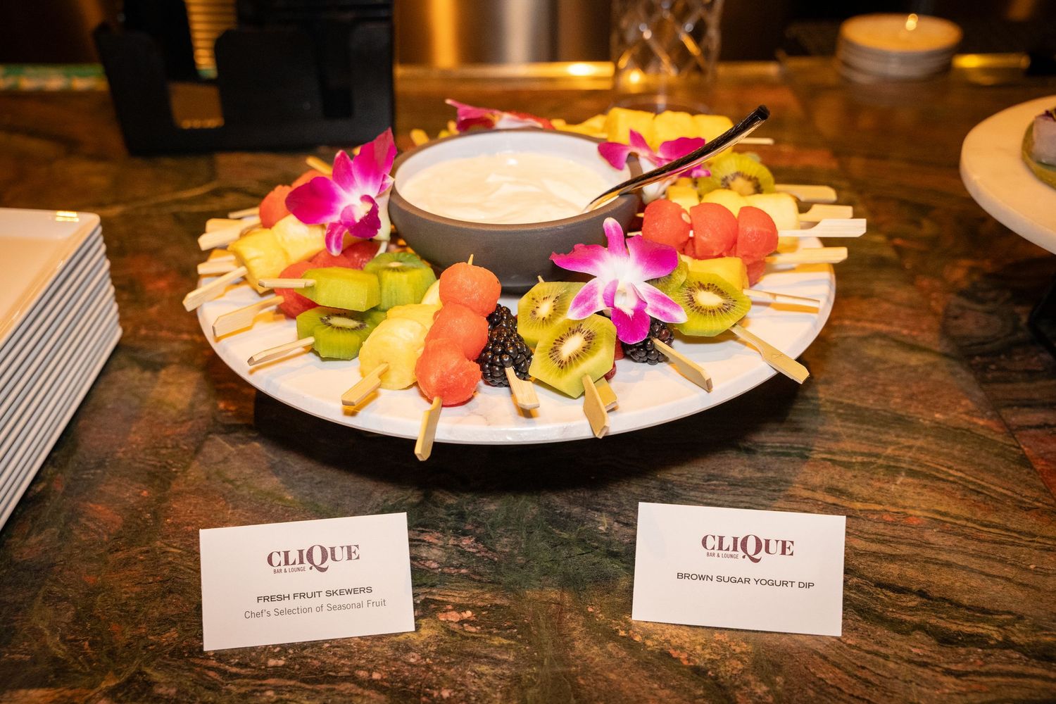 Colorful crudité platter with fresh vegetables and dip garnished with bright pink flowers.