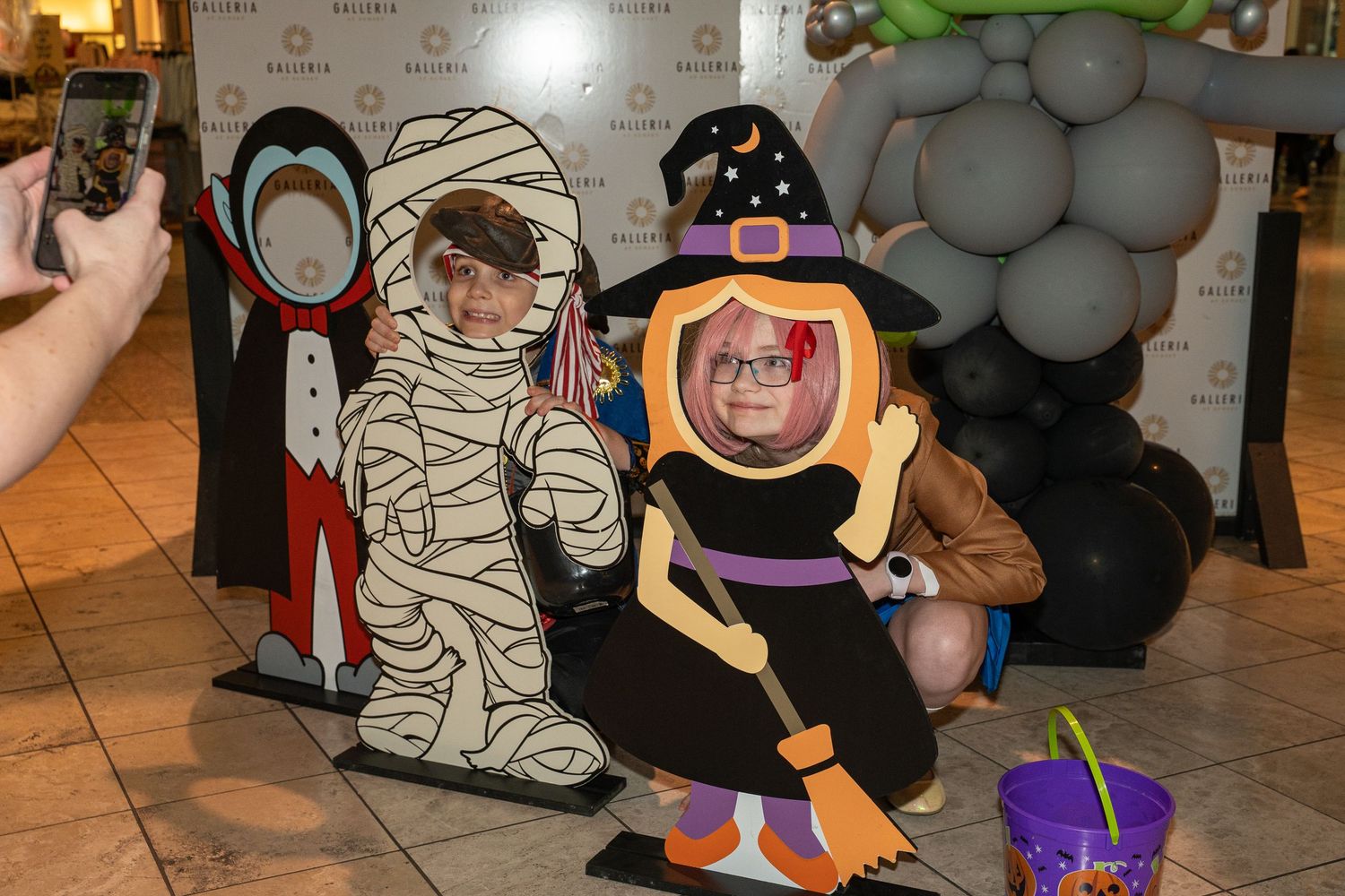 Halloween photo booth setup with spooky cutouts and decorations in a mall setting.