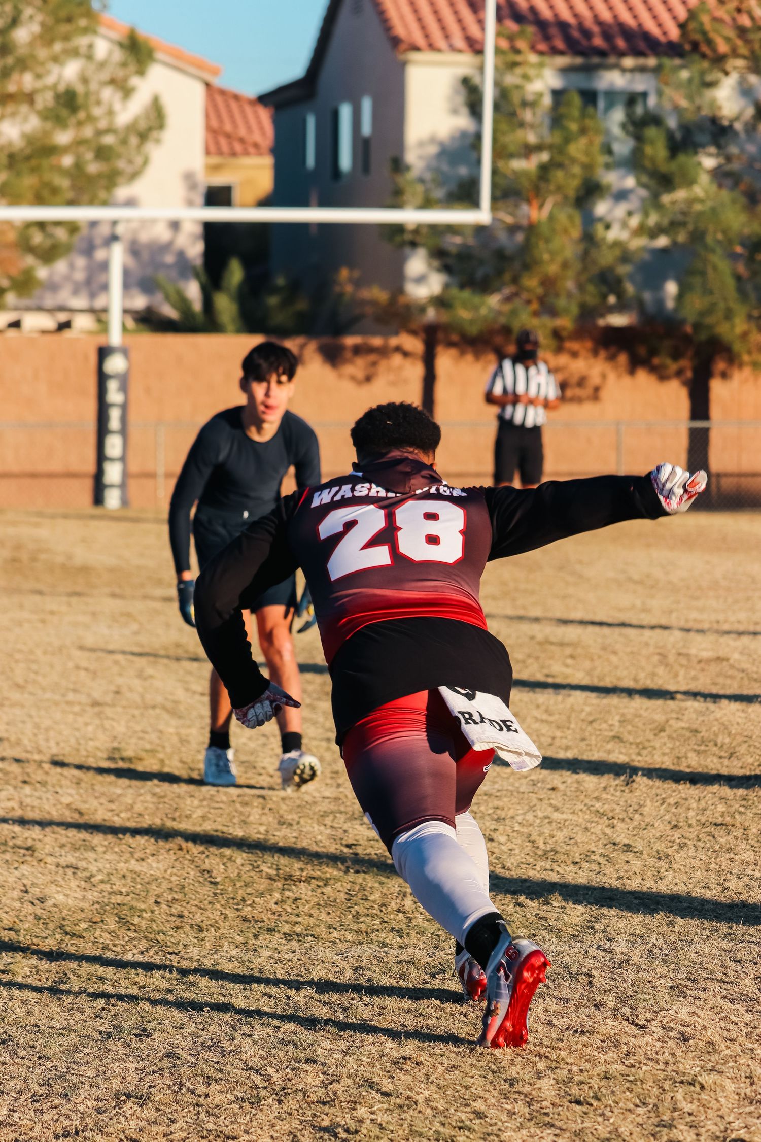 Player wearing number 28 reaches out to make a defensive play during a flag football game.