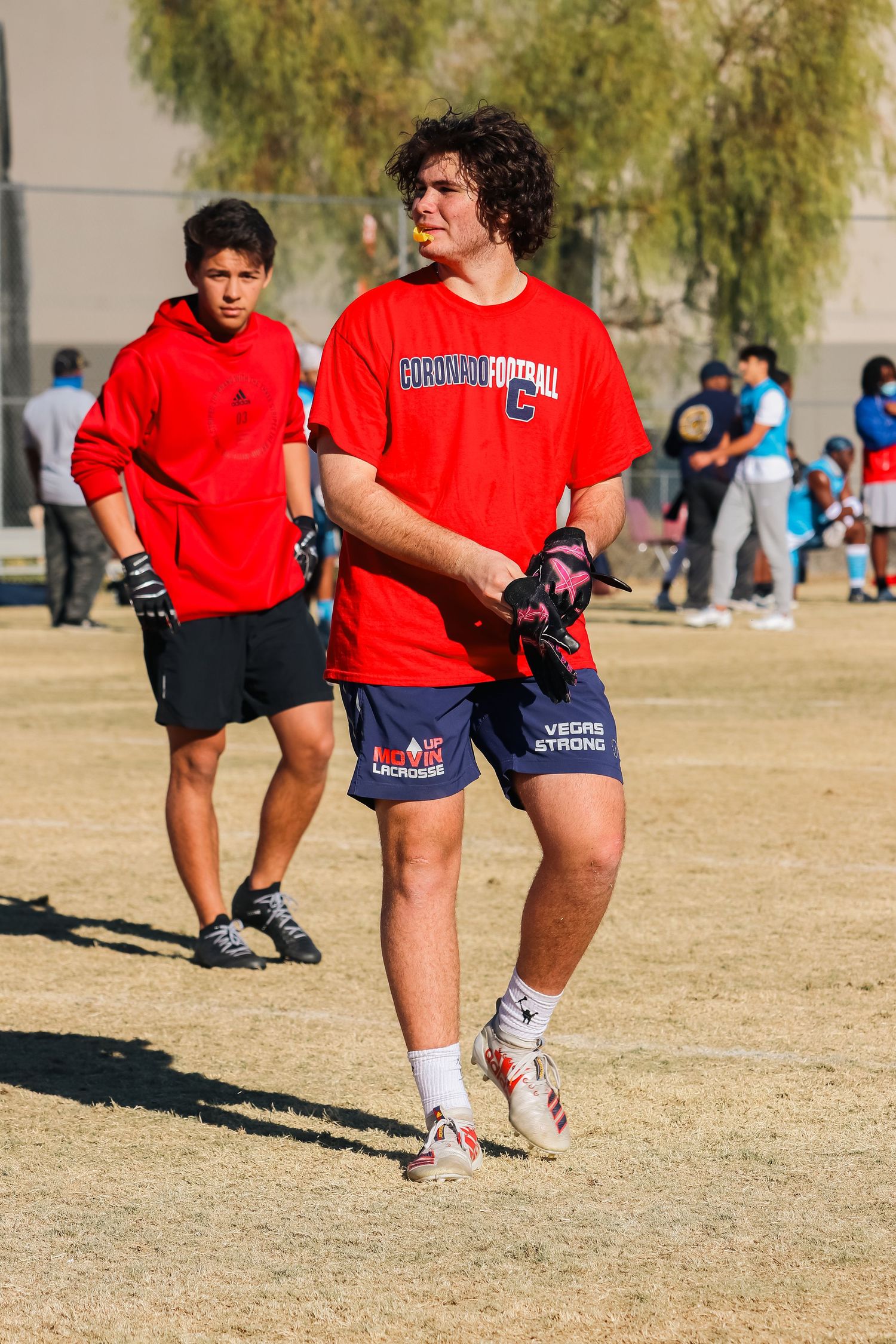 Players in red and navy sportswear participate in an outdoor football game.