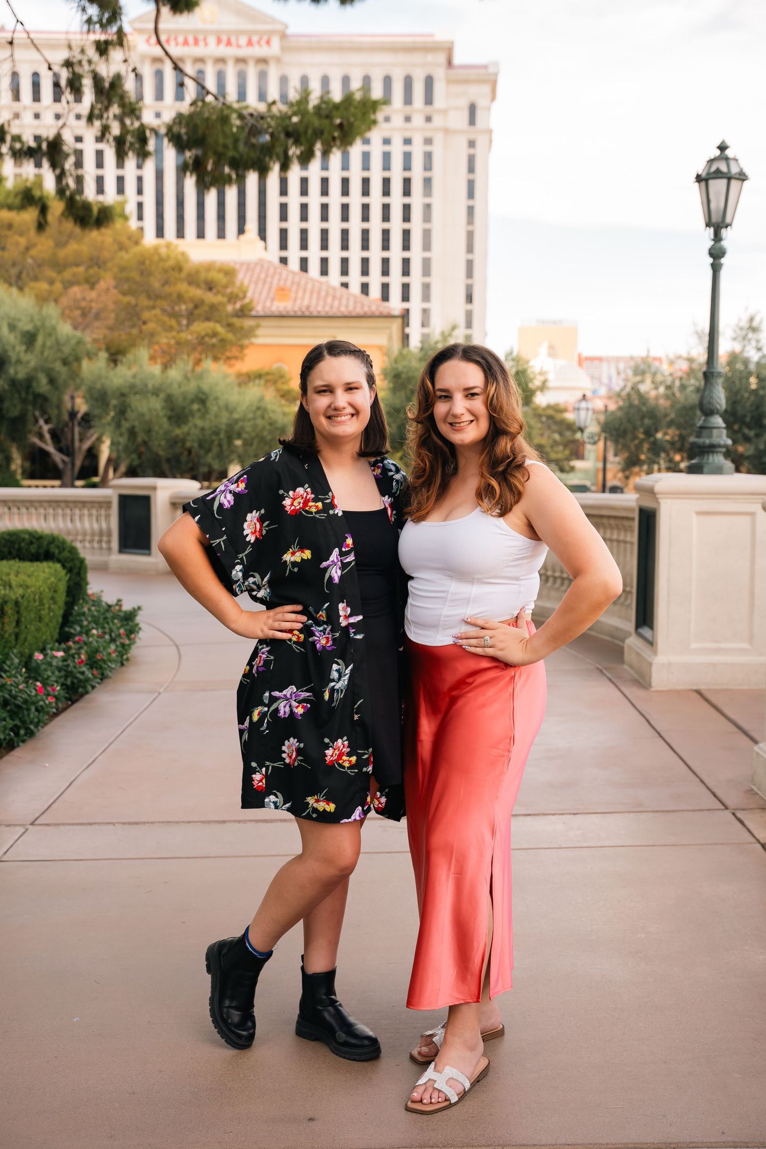 Two friends strike poses on a Las Vegas terrace with hotel buildings visible in background.
