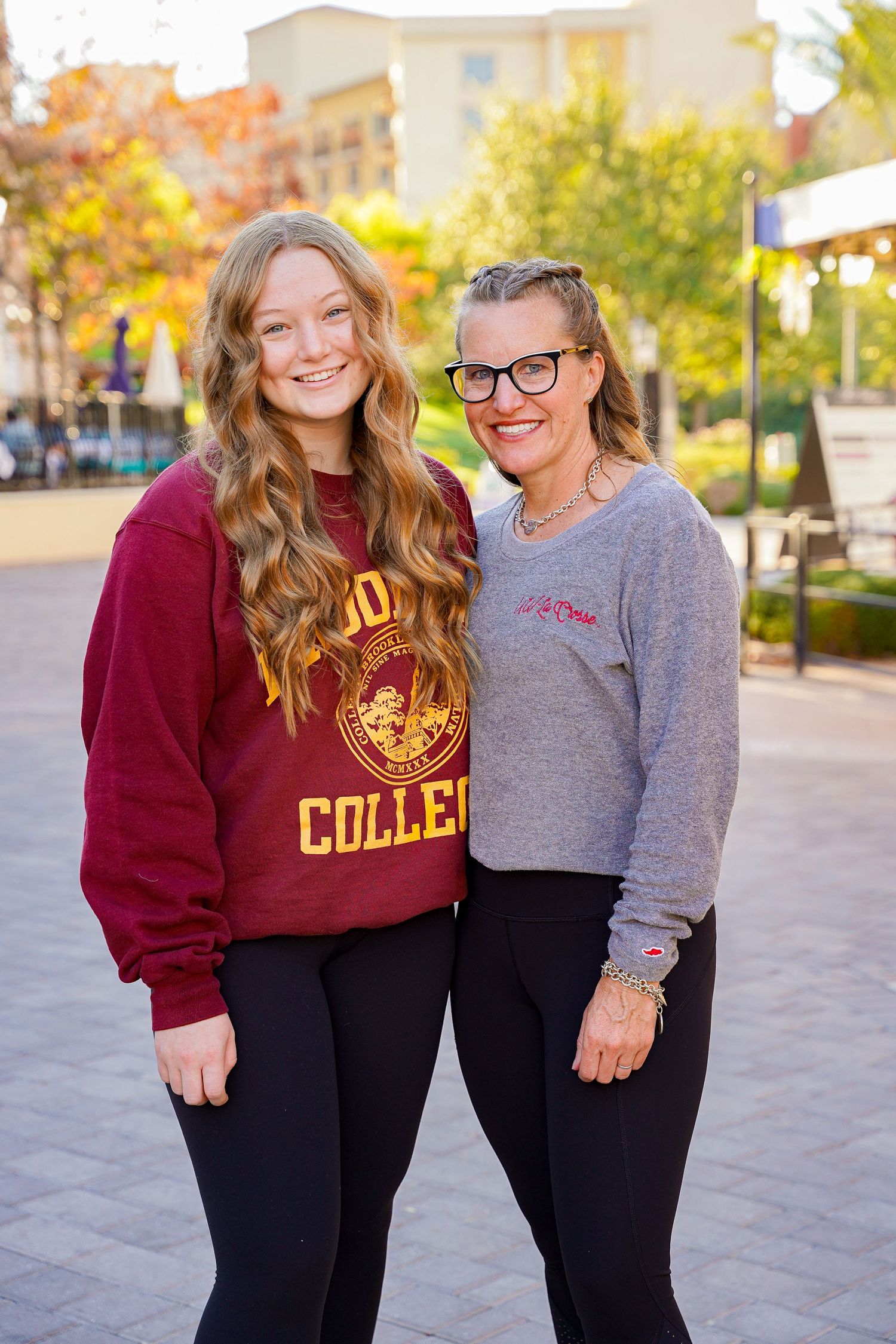 Friends in collegiate sweatshirts posing outdoors during autumn.