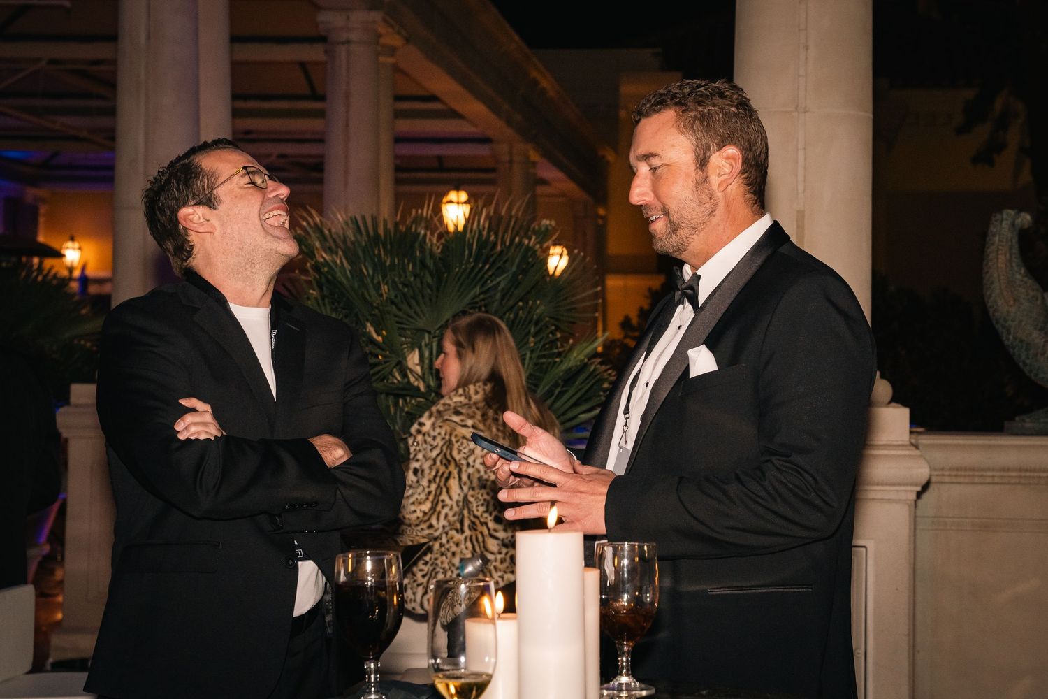 Two professionals in formal attire engaged in animated conversation at an evening event.