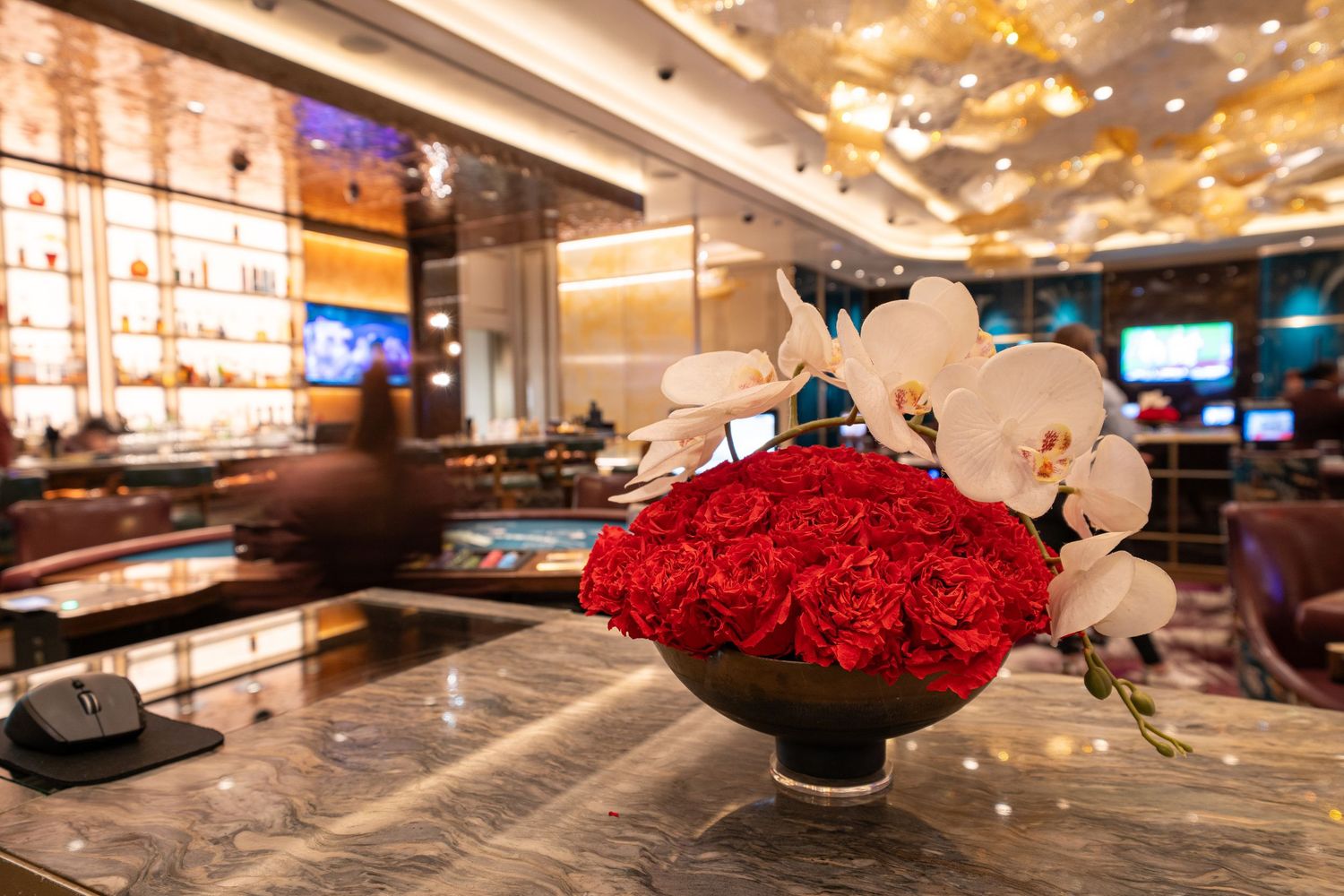 Elegant bar display with red roses and white orchids in a modern luxury setting.