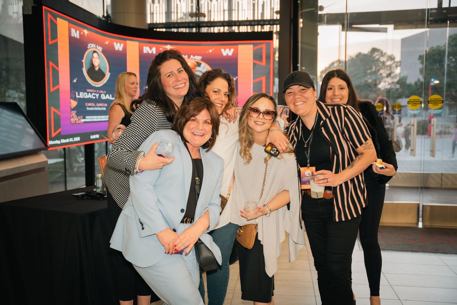 Casual group photo of friends at corporate event near window display.