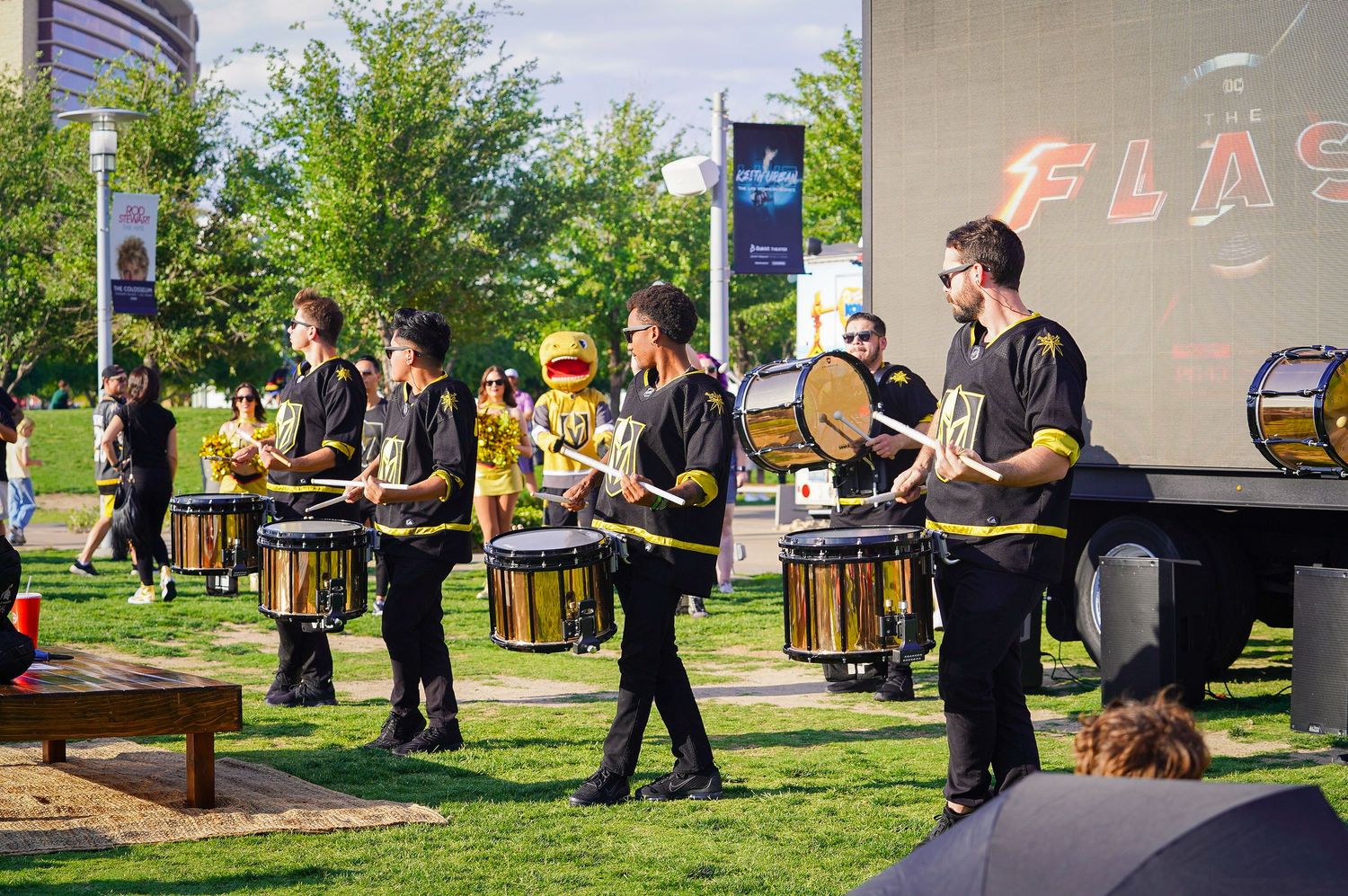 Drum line performers in black uniforms playing at outdoor Vegas Golden Knights event.
