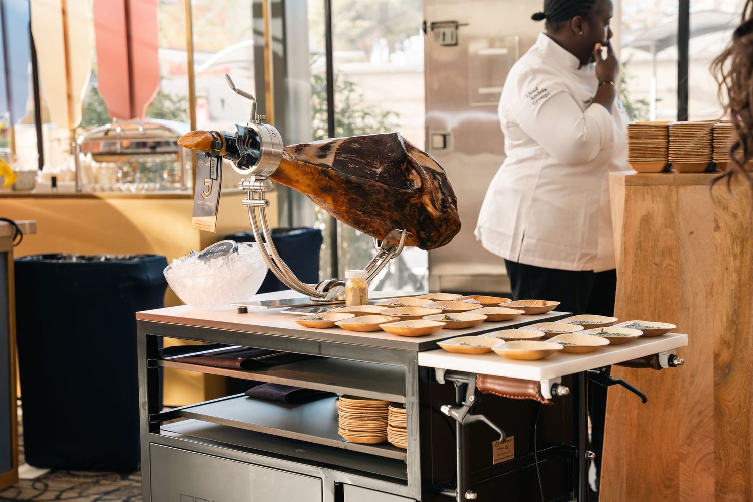 Restaurant kitchen setup with cooking equipment and staff member in white uniform working in background.