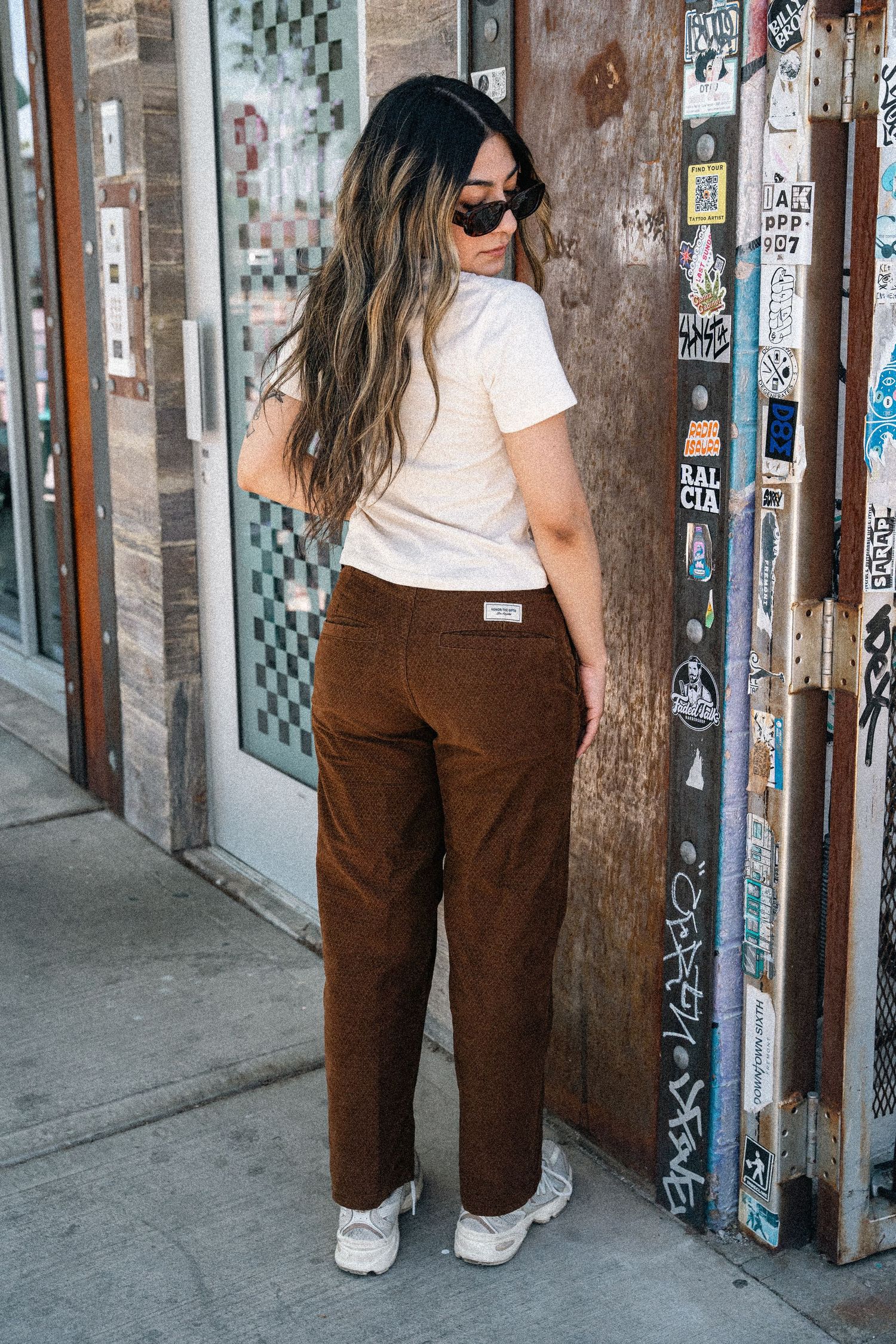 Back view of casual street style look with white t-shirt and brown corduroy pants.