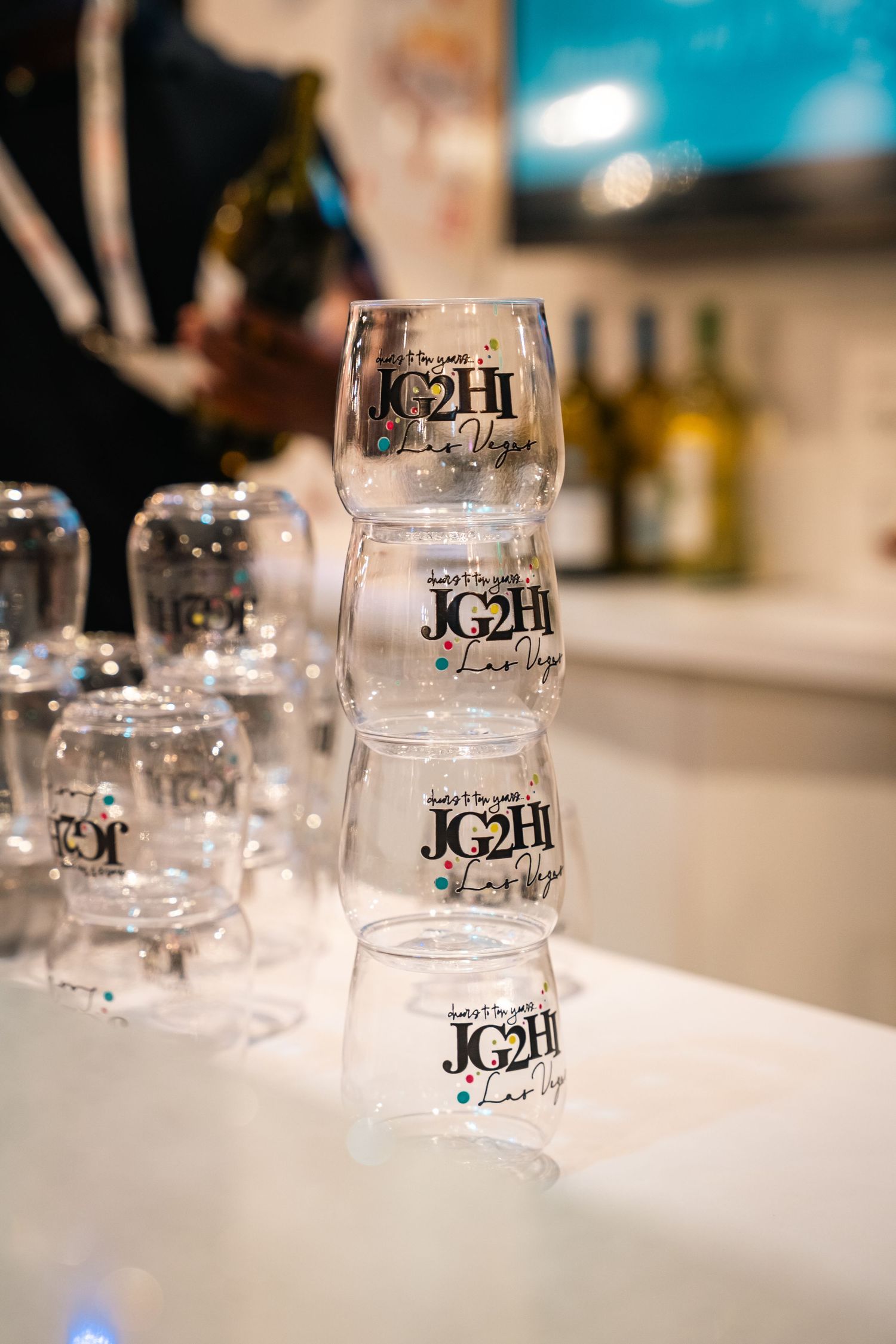Stack of branded JC2H glassware displayed at retail event.