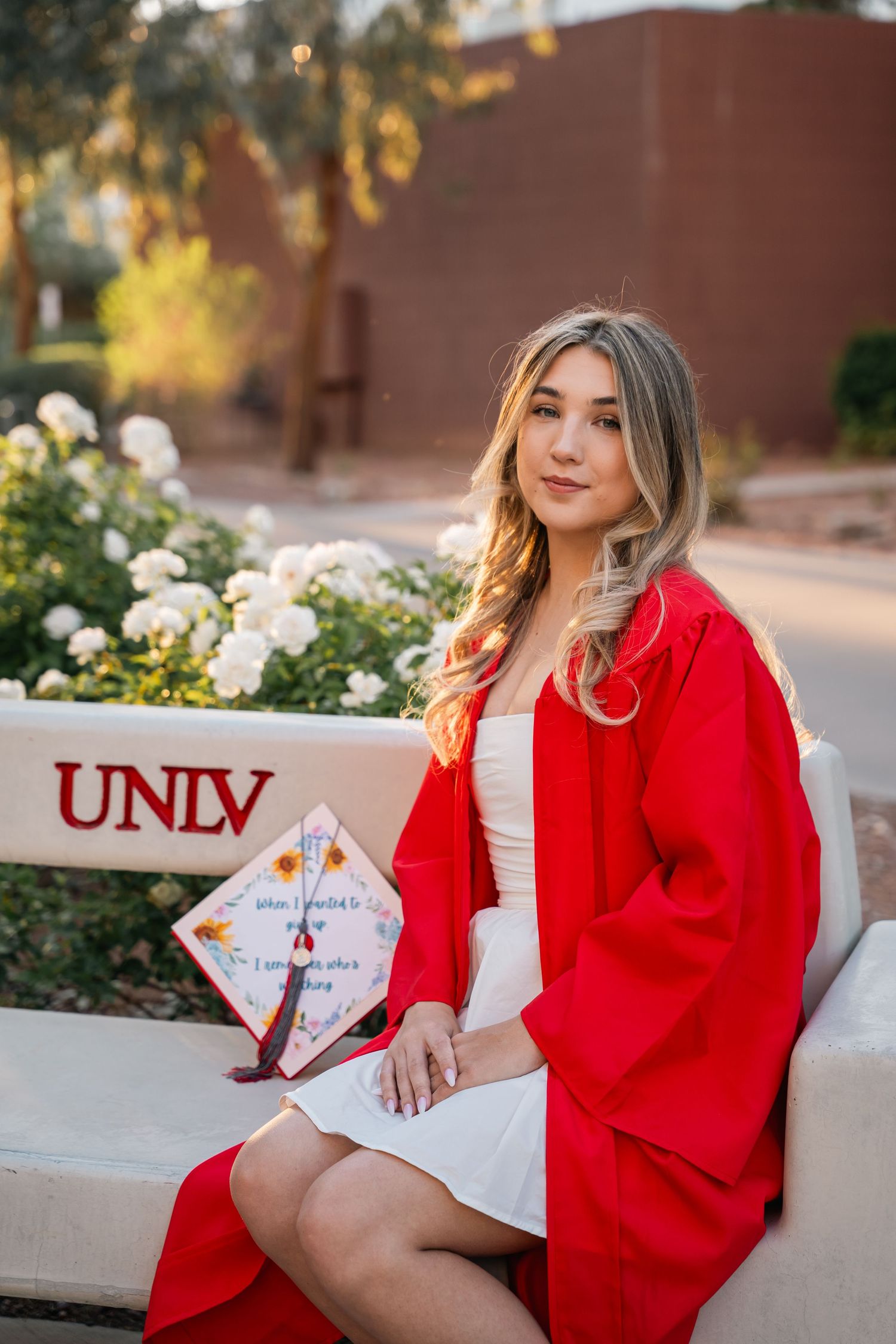 Graduation photos at UNLV campus with red gown and decorative cap.