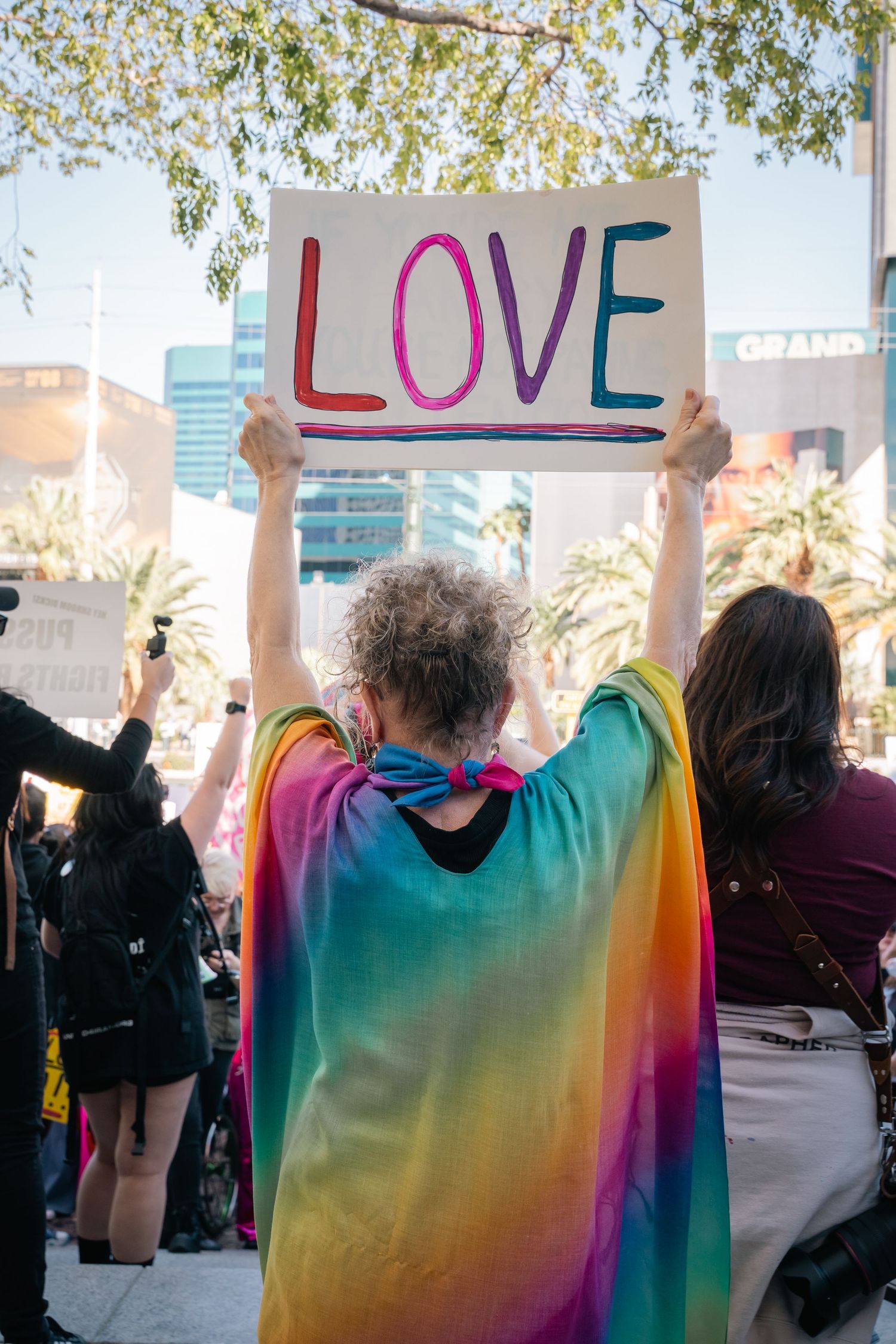 Demonstrators holding colorful rainbow signs displaying the word 'LOVE' at a protest.