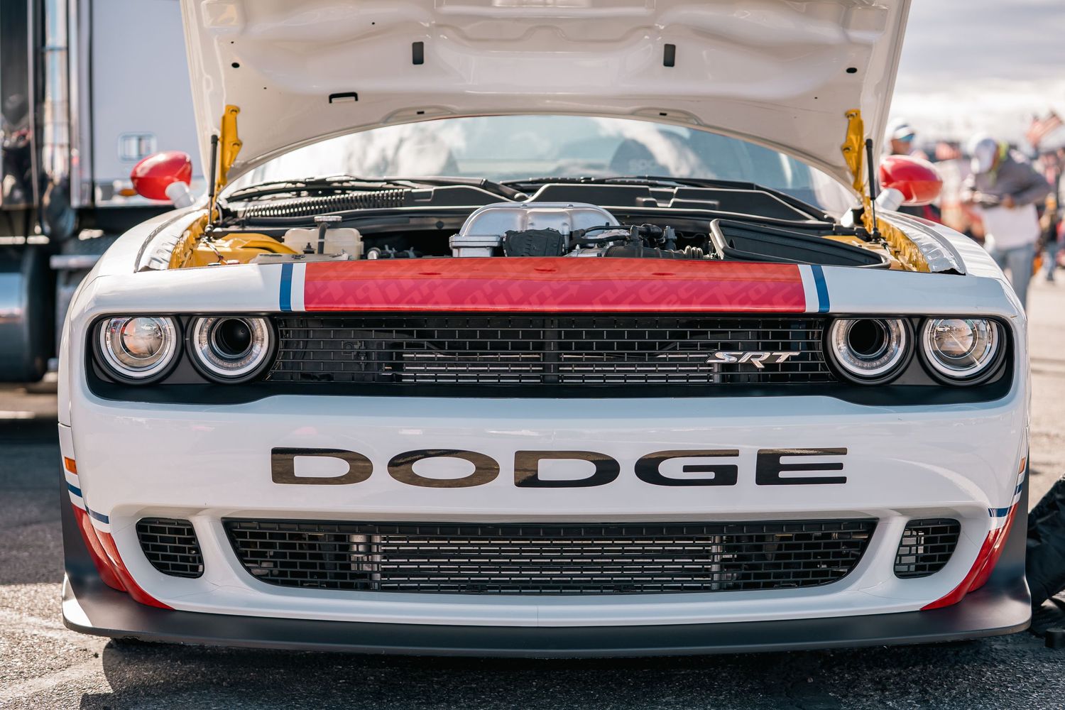 Close-up front view of white Dodge Challenger SRT with distinctive dual headlights at car show.