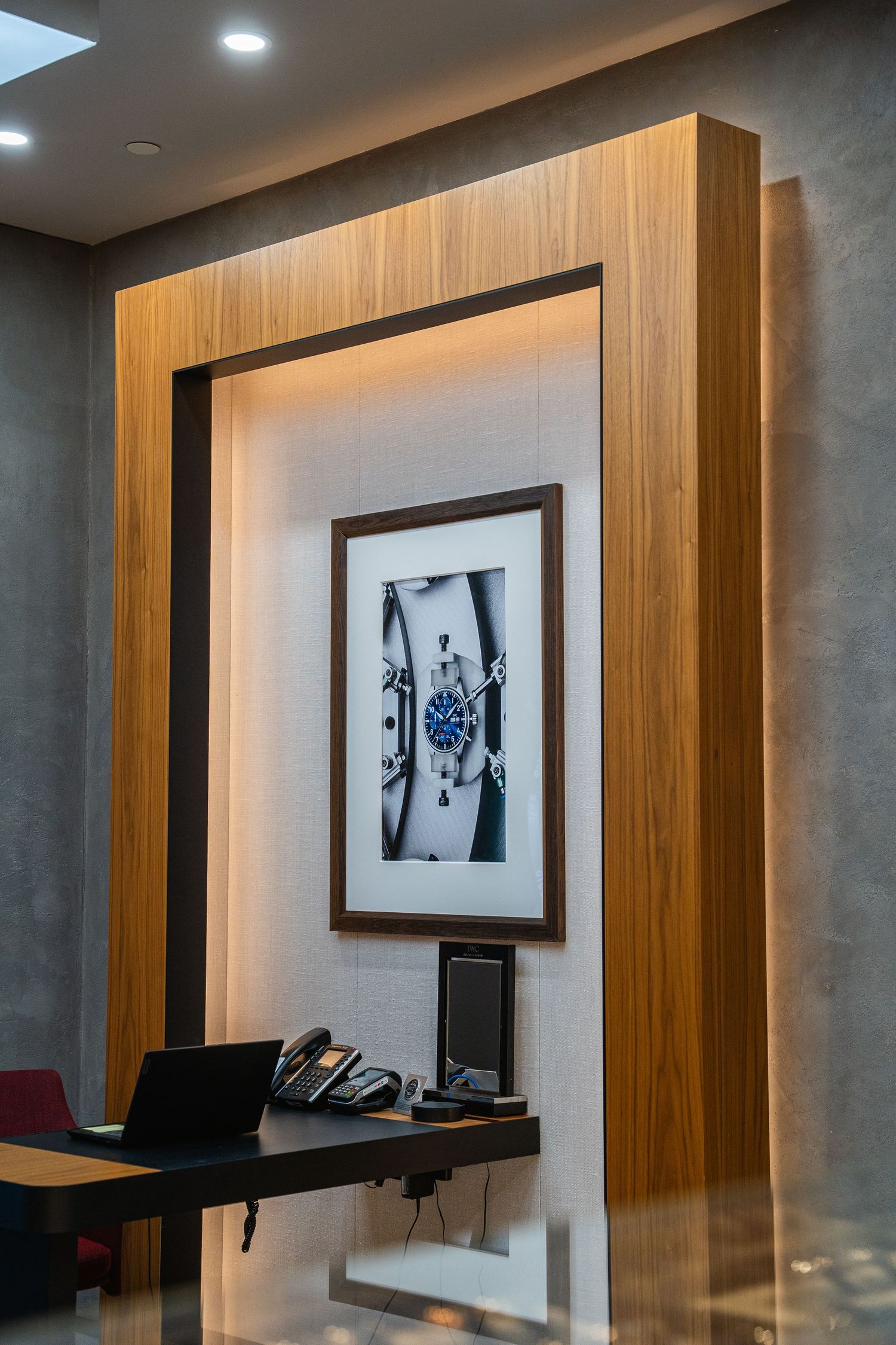 Modern wooden framed artwork display with backlighting in an office setting.