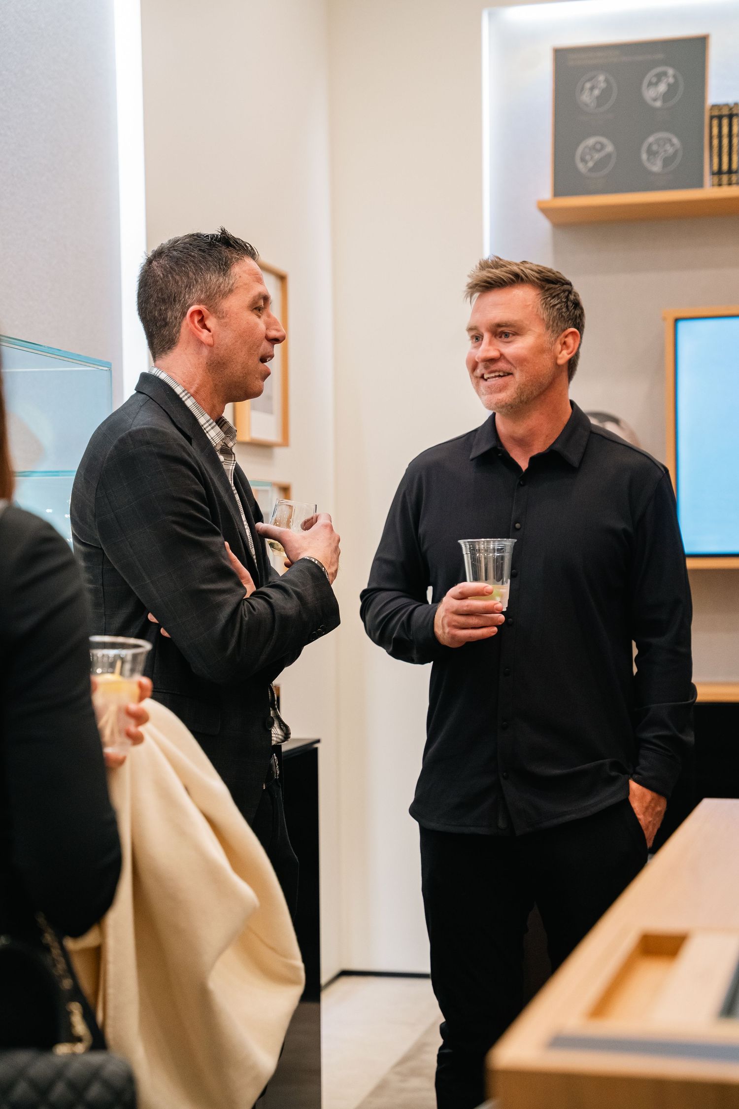 Two men in dark attire having conversation at upscale event.
