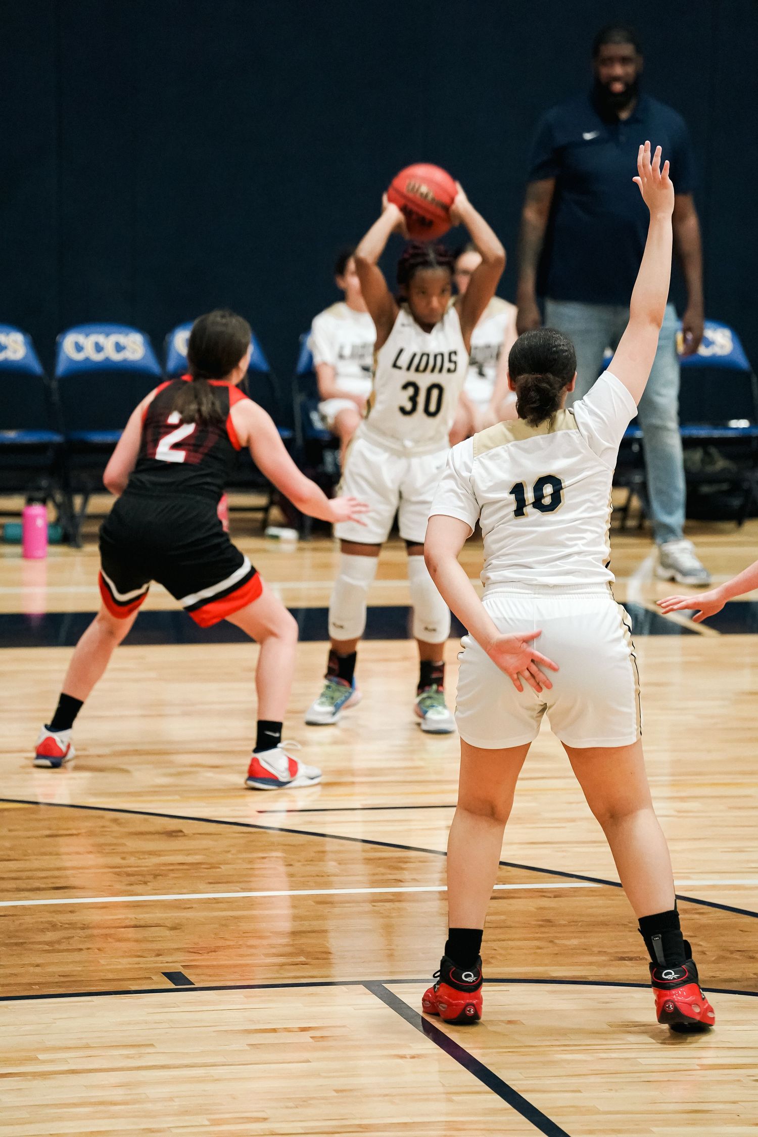 Players in white Lions uniforms practicing defensive stances during basketball practice.