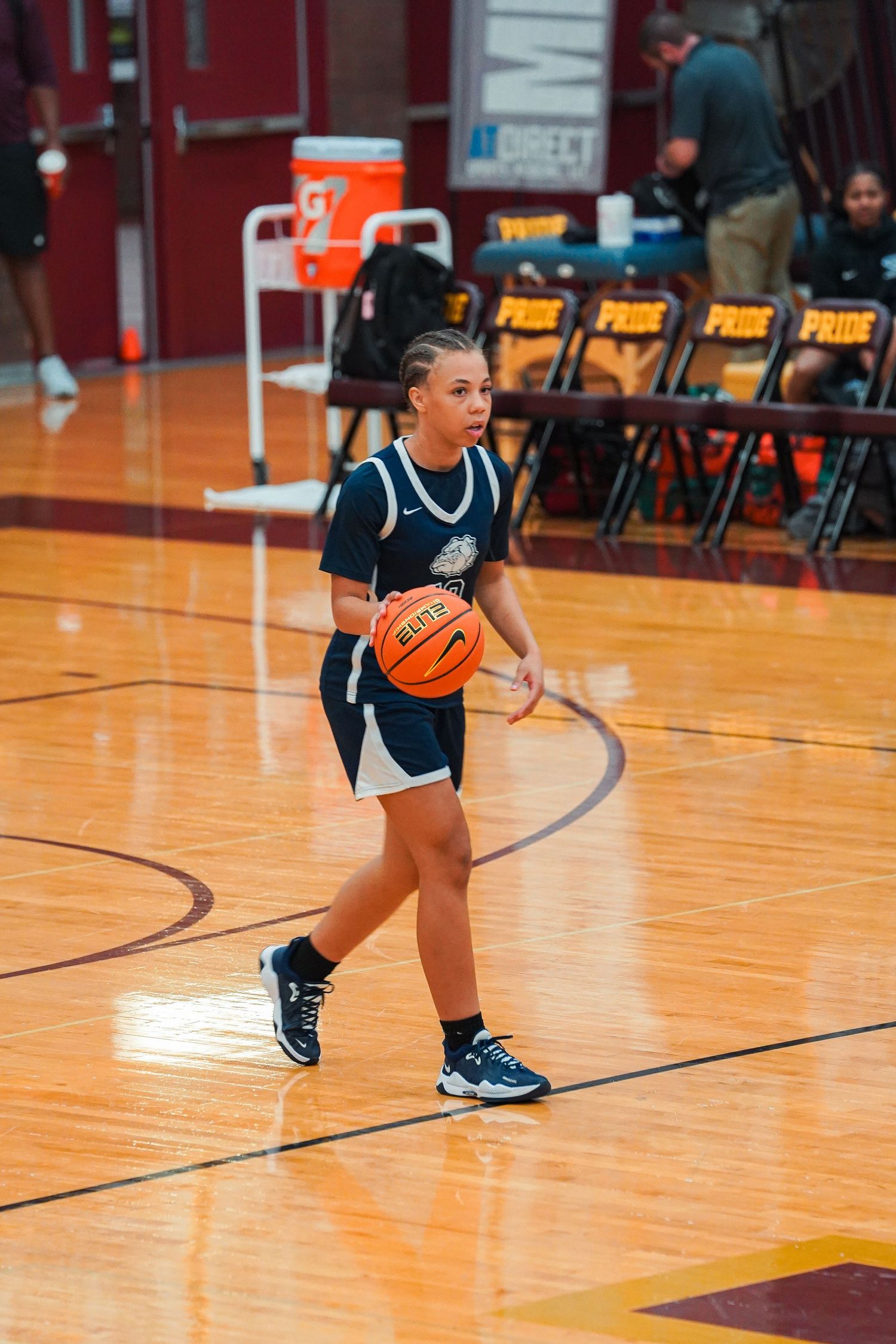 Players practice dribbling basketball drills across a brightly lit gymnasium court.