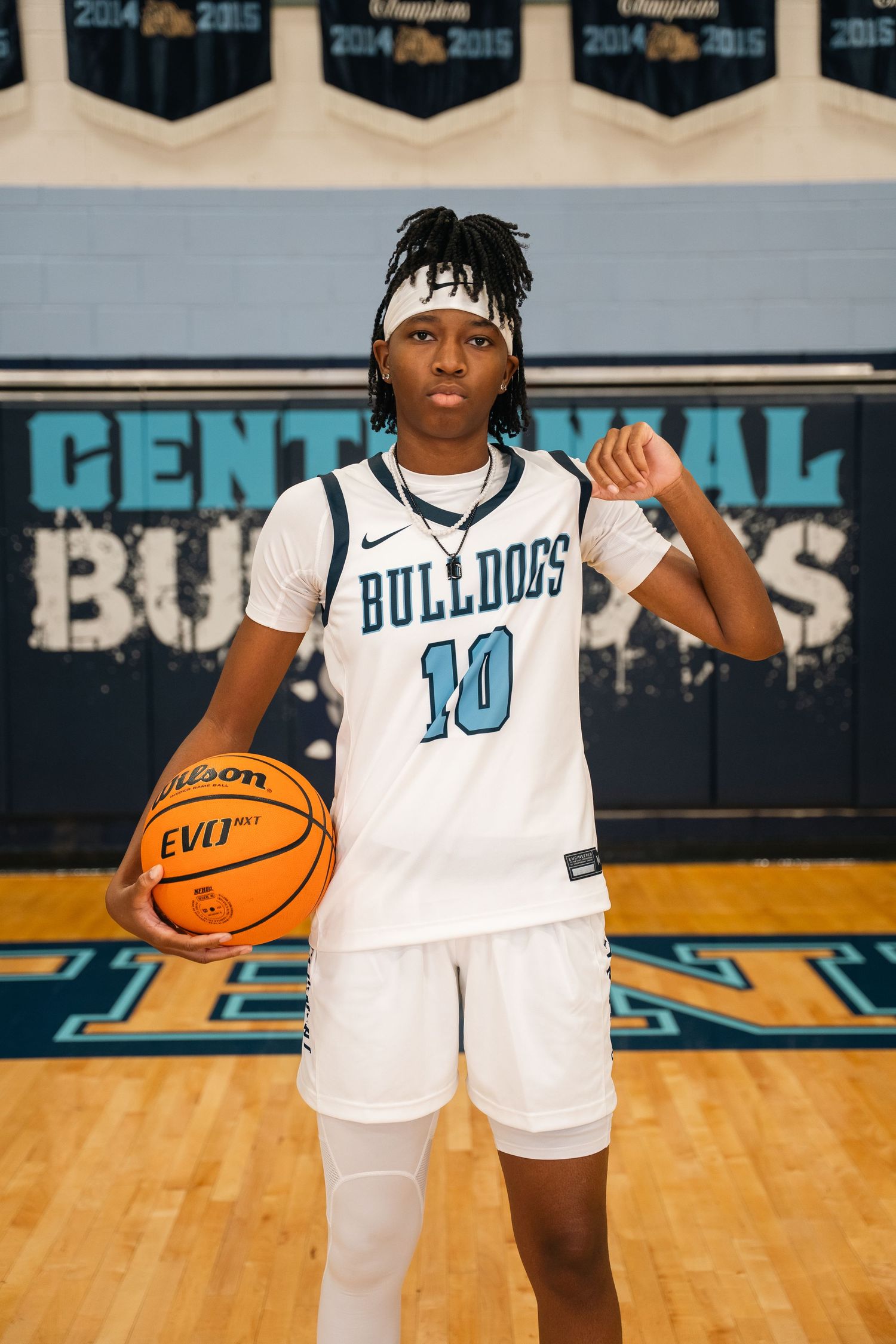 Basketball player in white Bulldogs jersey number 10 poses with orange ball on court.